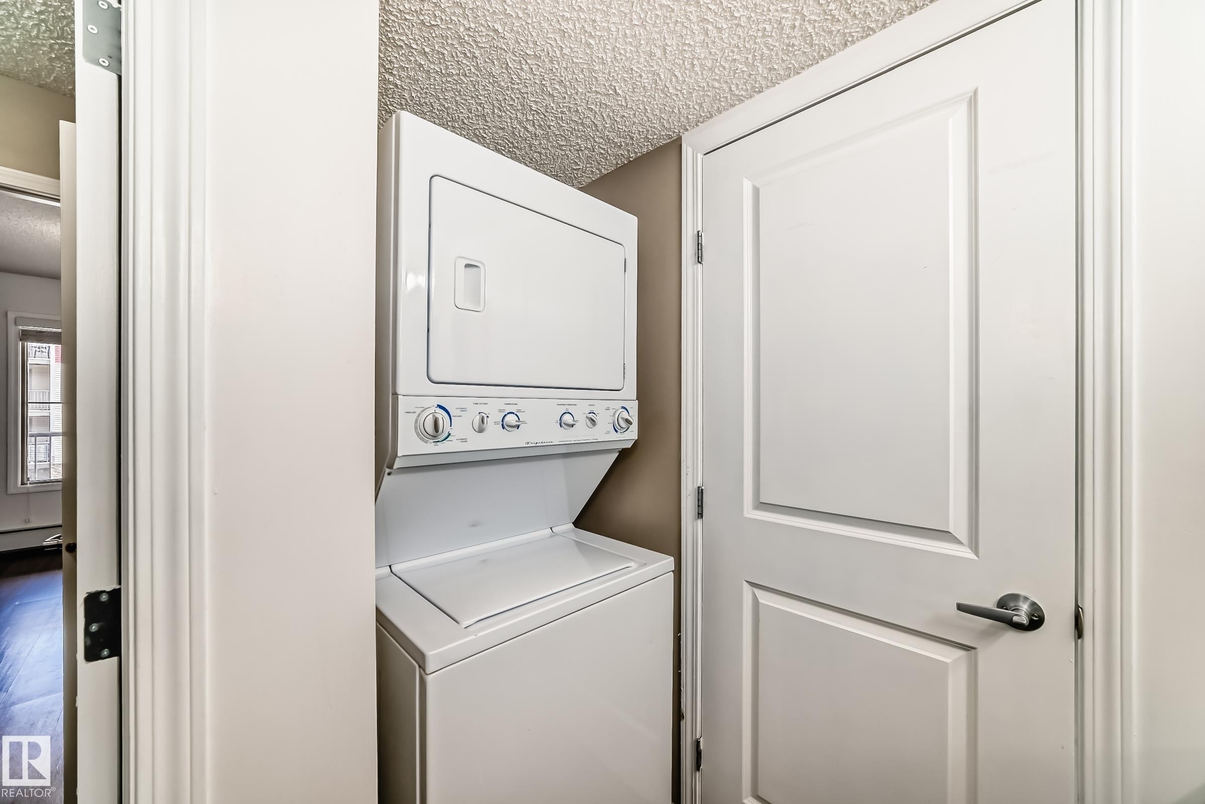 Laundry area featuring a stacked washer and dryer unit - 301 103 Ambleside Drive, Edmonton, AB - Indoor Photo Showing Laundry Room