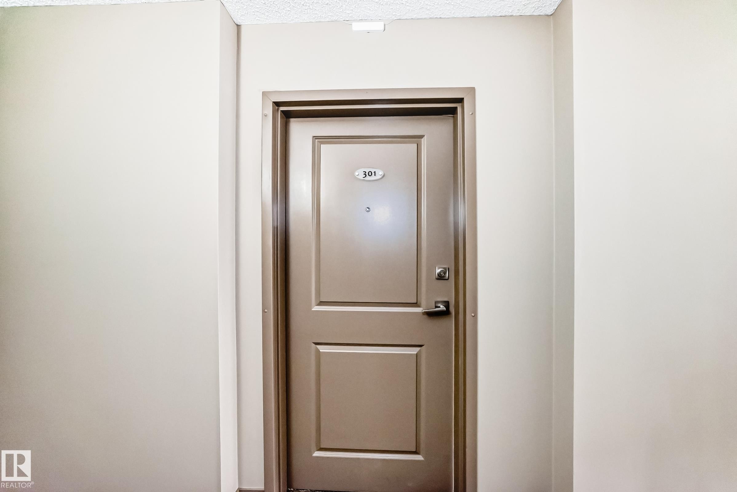 Entry door featuring a paneled design and a door handle - 301 103 Ambleside Drive, Edmonton, AB - Indoor Photo Showing Other Room