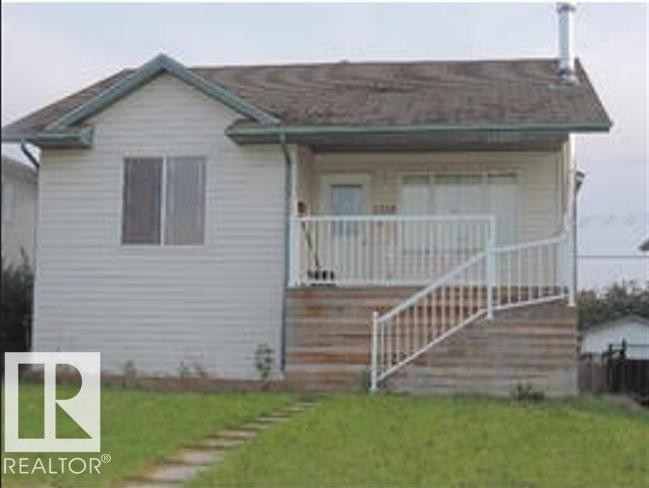 The property features a front lawn with a stone pathway, a wooden porch with white railings, and siding exterior - 1318 8 Avenue, Cold Lake, AB - Outdoor