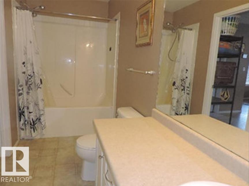 Bathroom featuring a bathtub with shower, a vanity with an integrated sink, and a toilet - 1318 8 Avenue, Cold Lake, AB - Indoor Photo Showing Bathroom