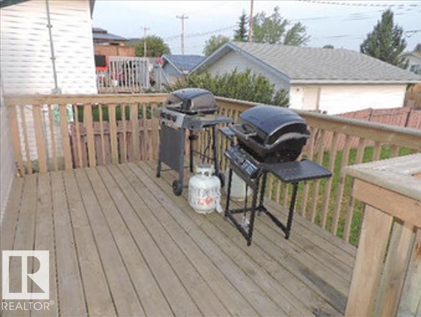 The property features a wooden deck with a wooden railing - 1318 8 Avenue, Cold Lake, AB - Outdoor With Deck Patio Veranda With Exterior
