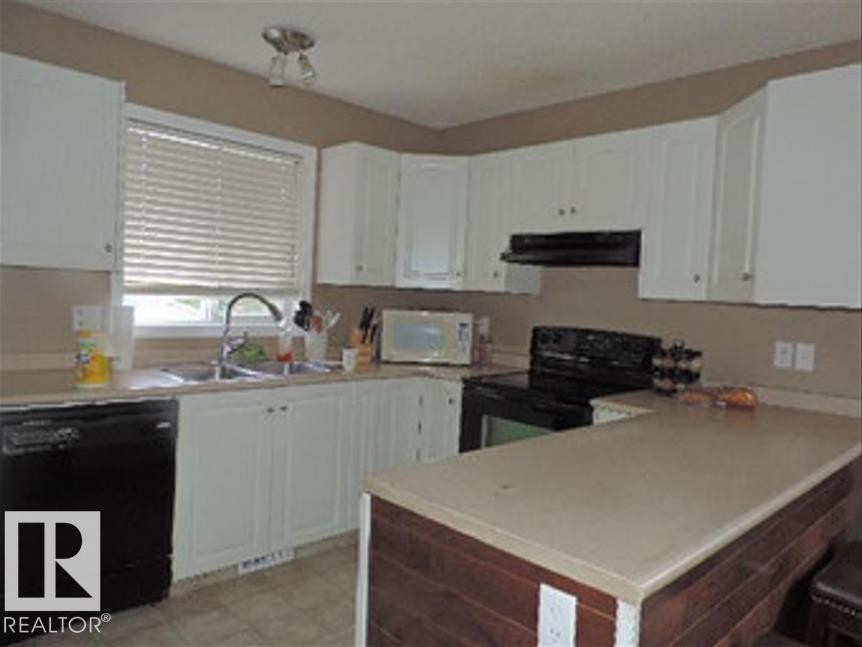 The kitchen features white cabinetry, a double basin sink, and a dishwasher - 1318 8 Avenue, Cold Lake, AB - Indoor Photo Showing Kitchen With Double Sink