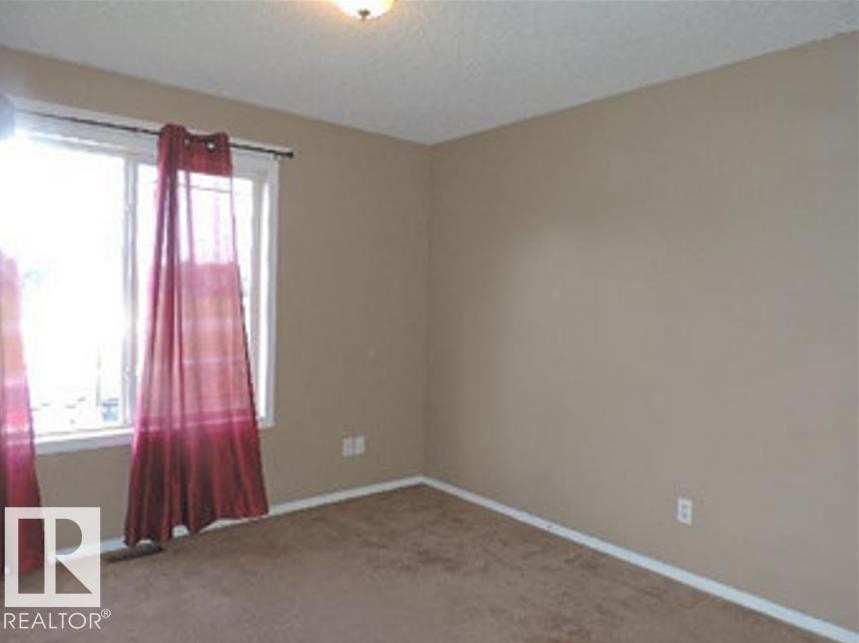 Interior room with neutral-toned walls, brown carpeting, and a window providing natural light - 1318 8 Avenue, Cold Lake, AB - Indoor Photo Showing Other Room