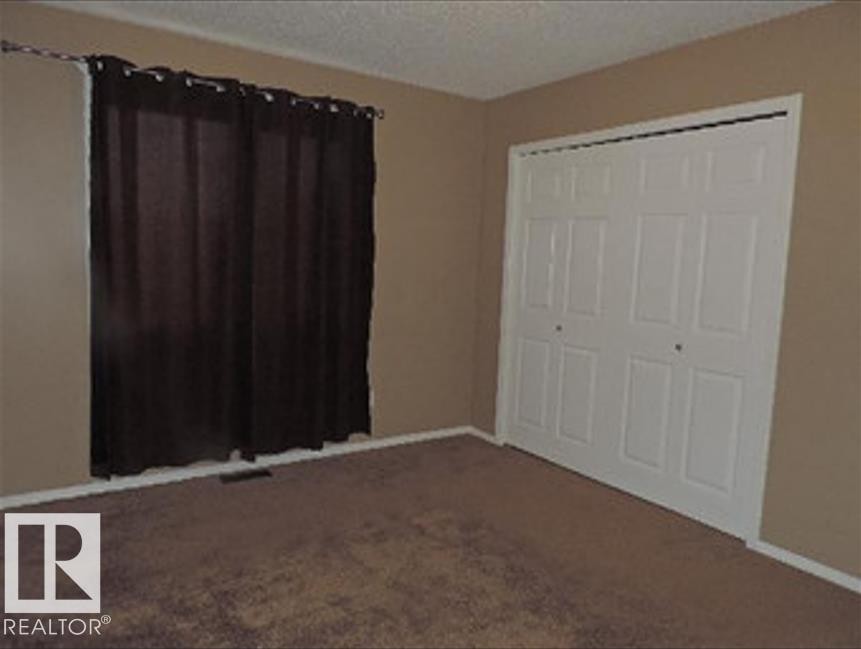 The room features neutral-toned walls, brown carpeting, and white baseboards - 1318 8 Avenue, Cold Lake, AB - Indoor Photo Showing Other Room