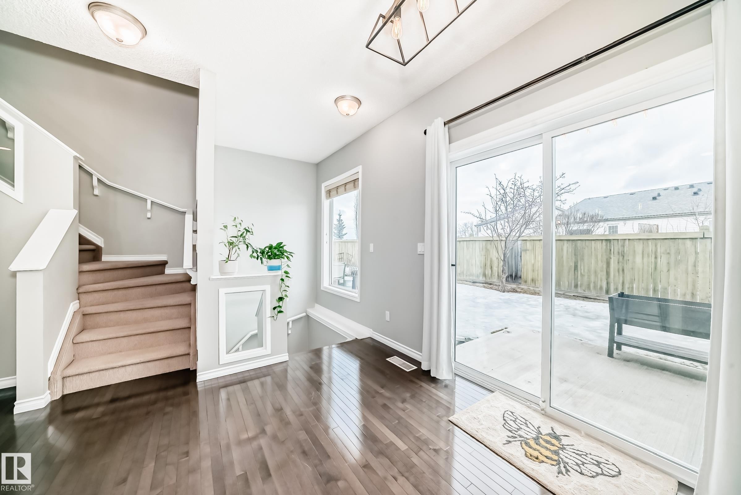 The property features rich dark wood flooring and a staircase with light-colored carpeting and white railings - 105 13825 155 Avenue, Edmonton, AB - Indoor Photo Showing Other Room