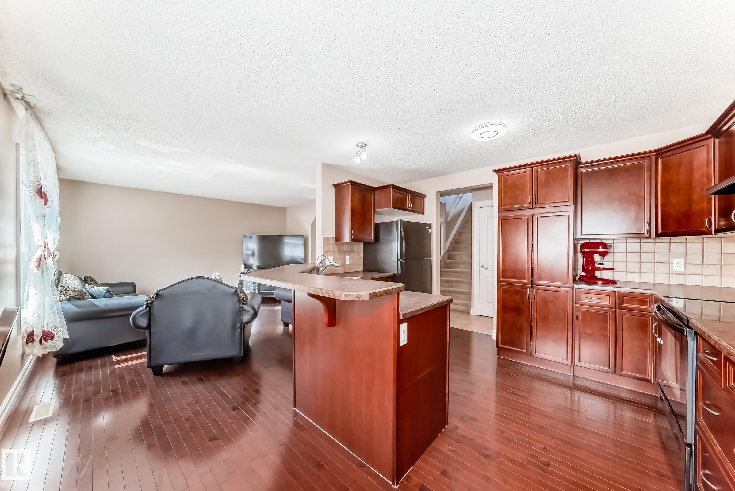 The property features an open-concept layout with hardwood flooring throughout the main living areas - 11415 167A Avenue Nw, Edmonton, AB - Indoor Photo Showing Kitchen