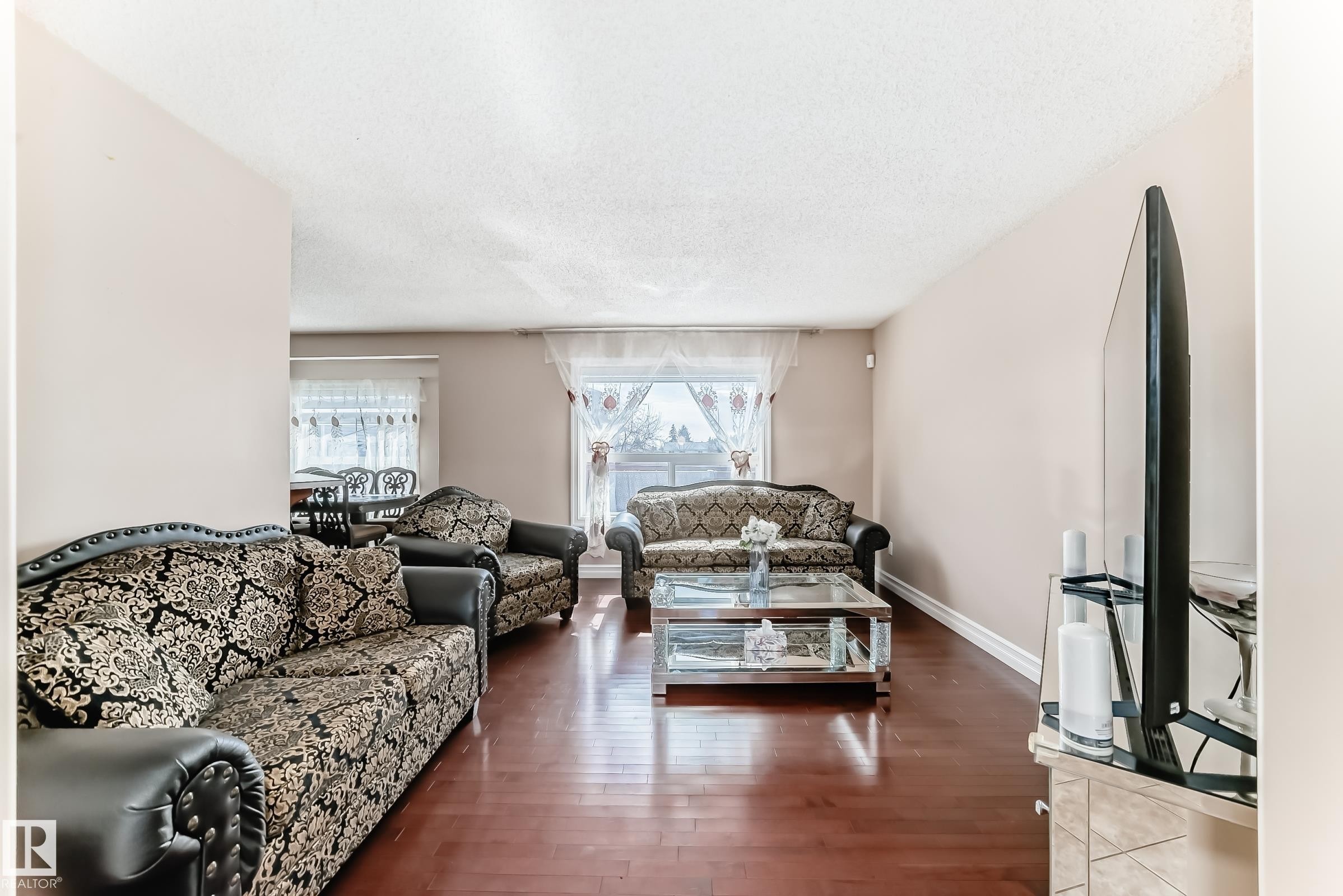 Living room featuring hardwood floors, light-colored walls, and a large window providing natural light - 11415 167A Avenue Nw, Edmonton, AB - Indoor Photo Showing Living Room