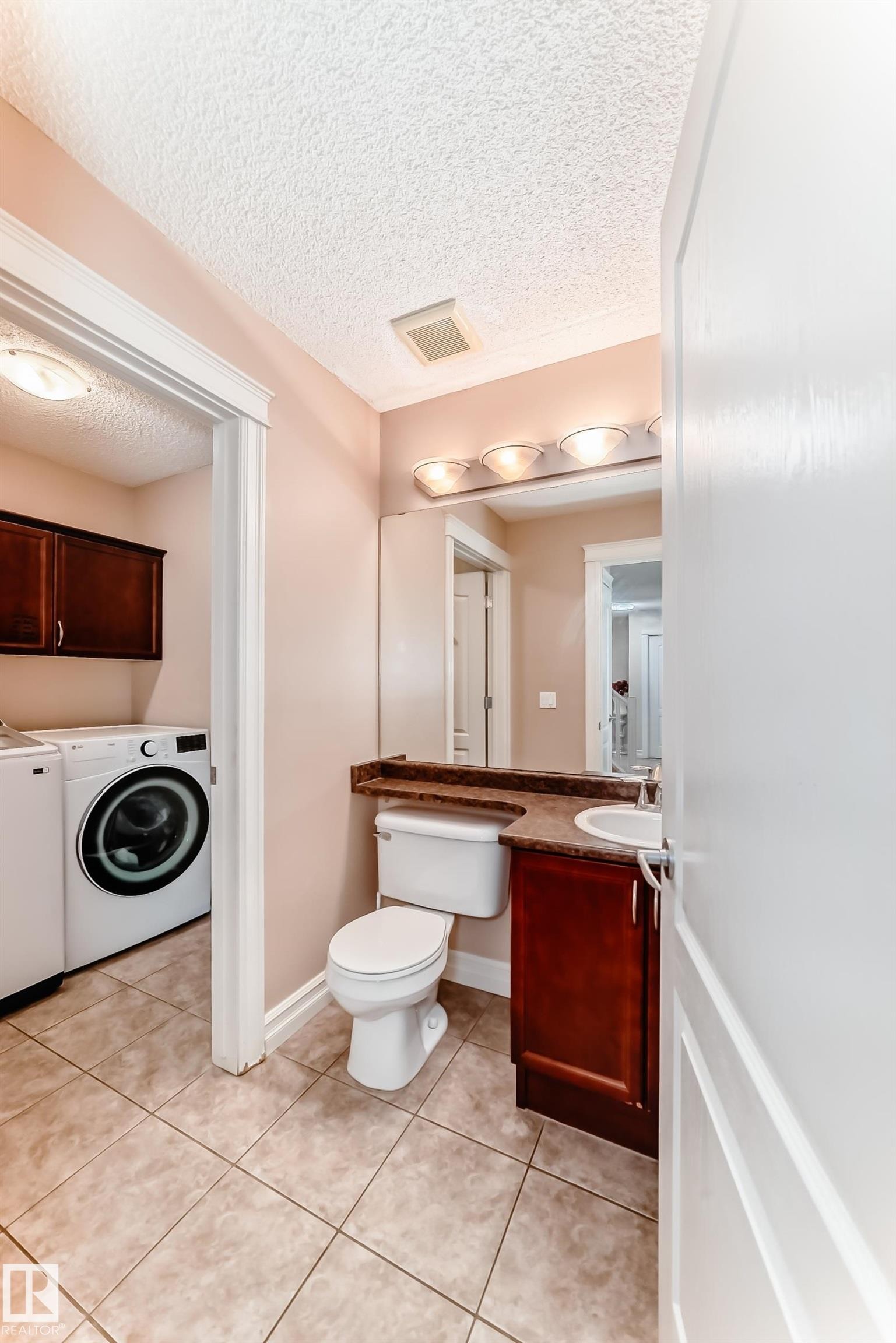 This utility room features a toilet, a vanity with a sink, and tiled flooring - 11415 167A Avenue Nw, Edmonton, AB - Indoor Photo Showing Laundry Room