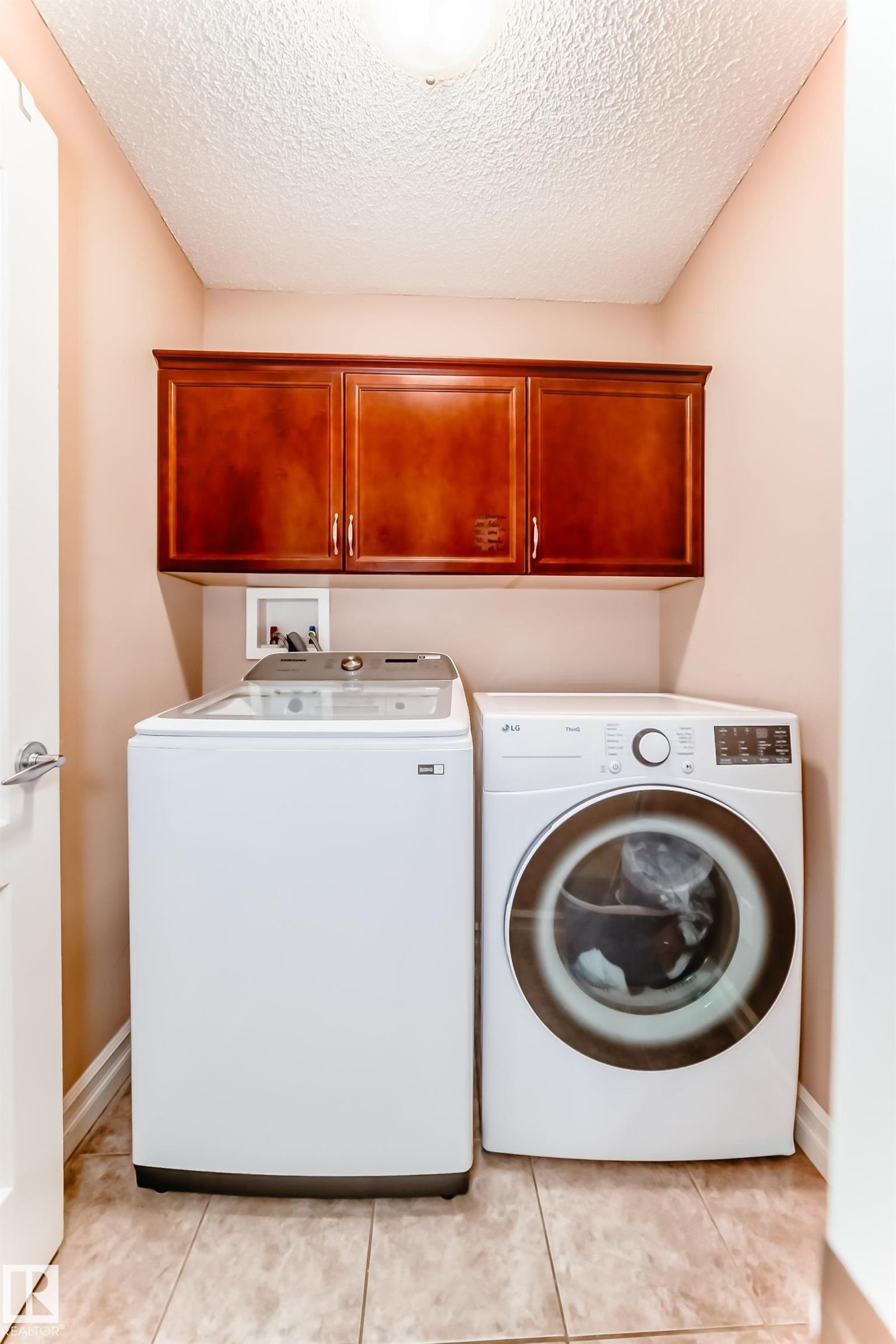 Dedicated laundry area with upper cabinetry, tiled flooring, and modern appliances - 11415 167A Avenue Nw, Edmonton, AB - Indoor Photo Showing Laundry Room