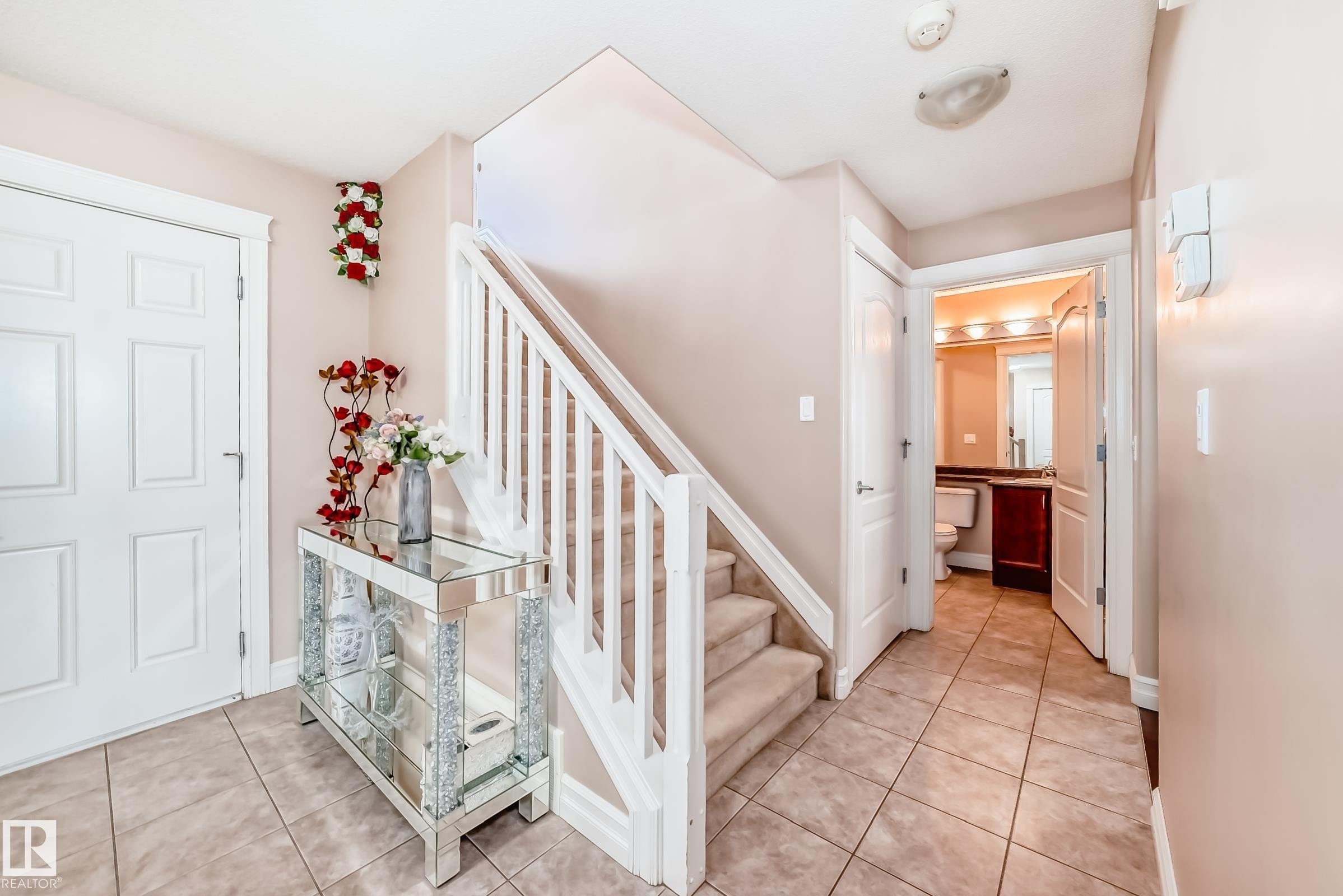 This property features a tiled entryway with a carpeted staircase and a white banister - 11415 167A Avenue Nw, Edmonton, AB - Indoor Photo Showing Other Room