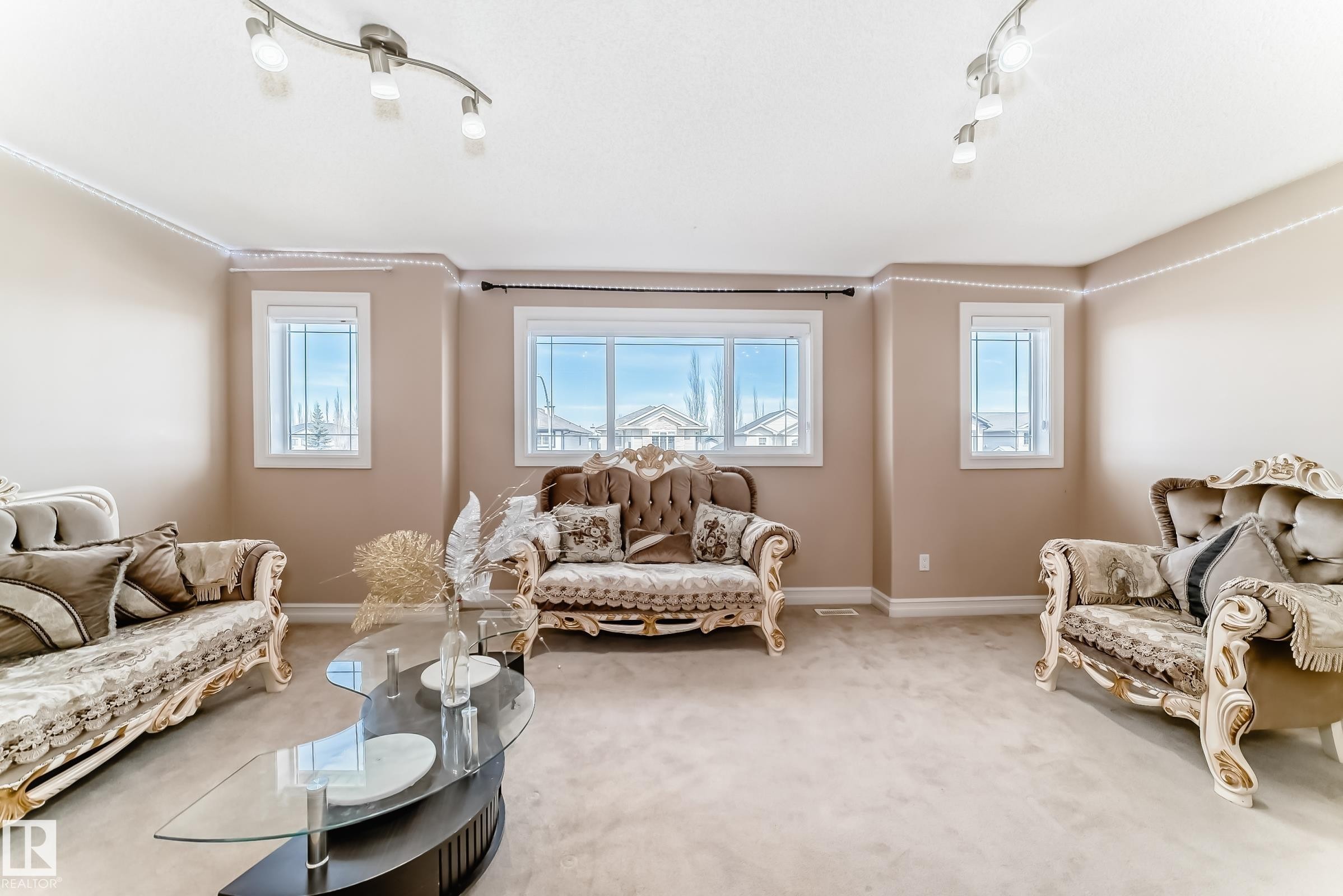 The living area features neutral-toned walls, windows providing natural light, and track lighting fixtures on the ceiling - 11415 167A Avenue Nw, Edmonton, AB - Indoor Photo Showing Living Room