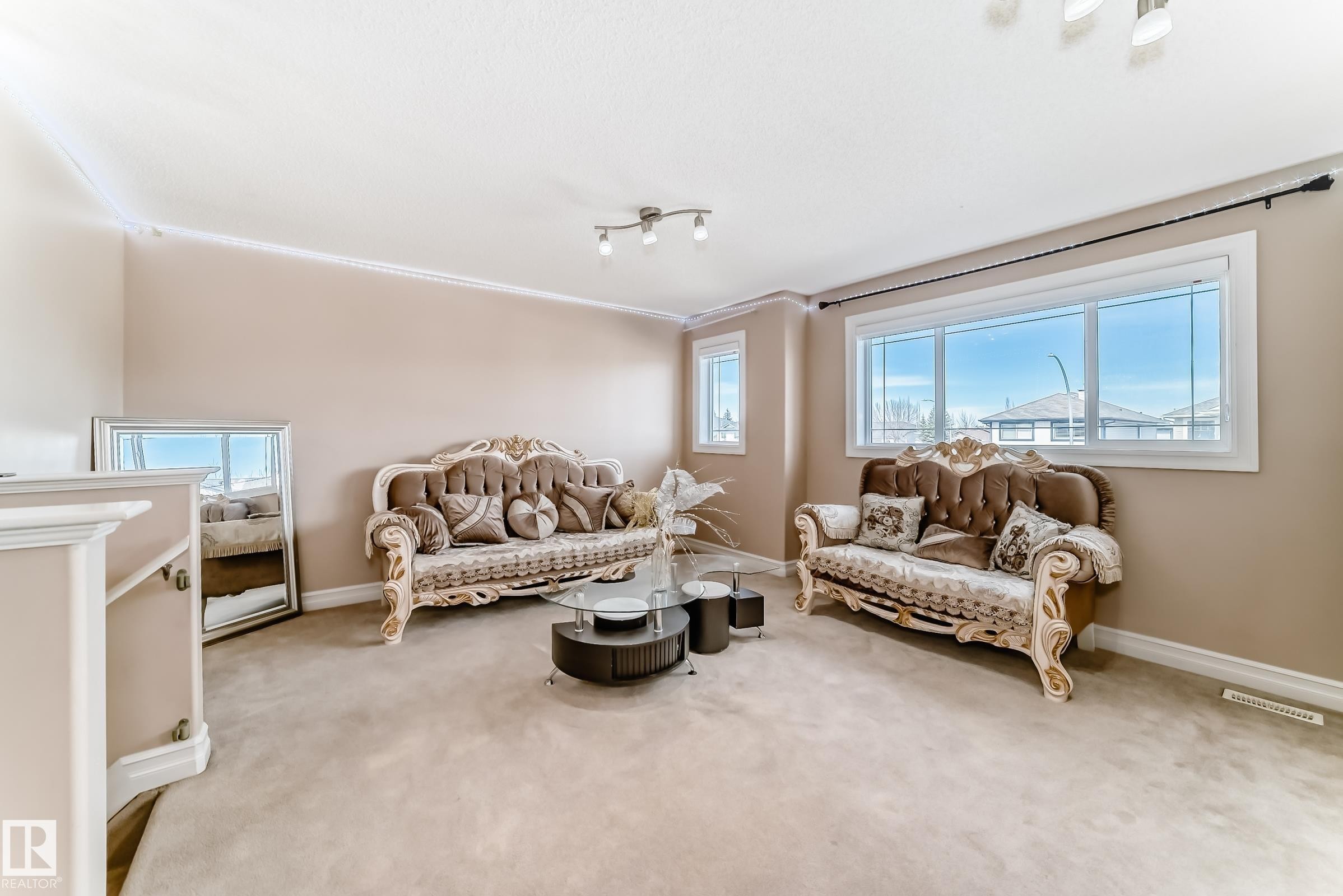 This expansive living space features large windows, crown molding, and neutral-toned walls, creating a bright and inviting atmosphere - 11415 167A Avenue Nw, Edmonton, AB - Indoor Photo Showing Living Room