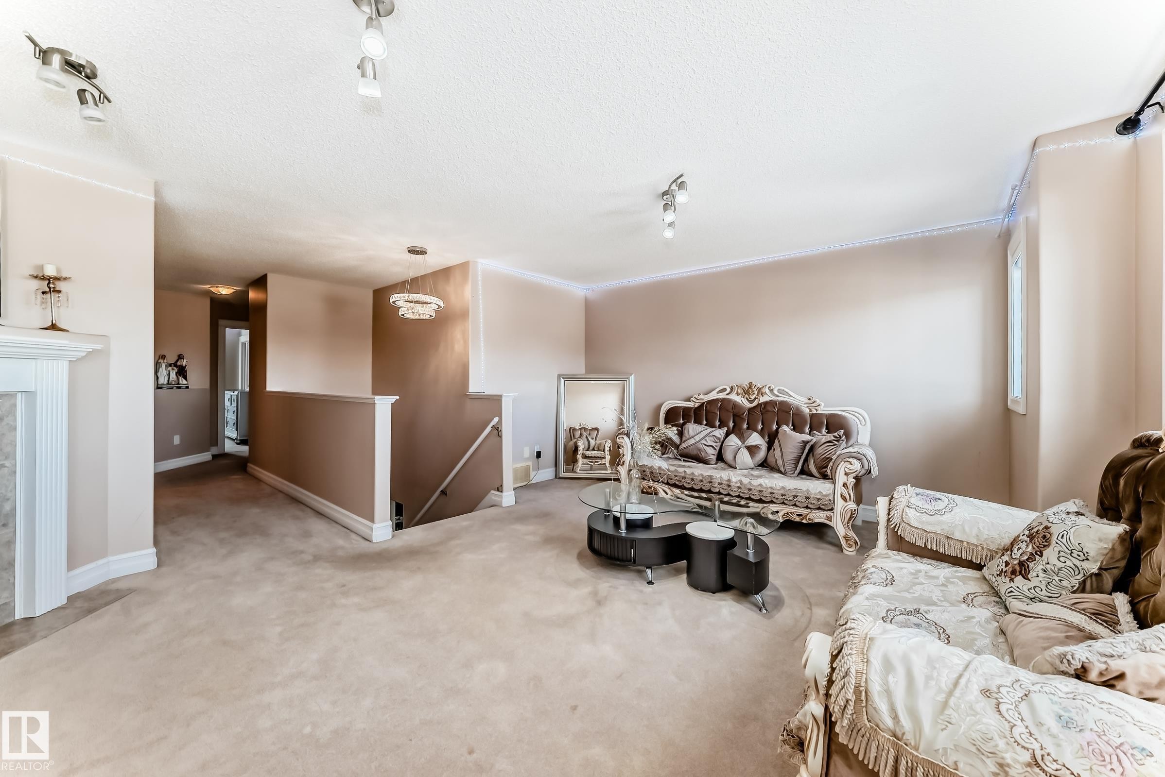 This living area features neutral-toned walls, carpeted flooring, and crown molding - 11415 167A Avenue Nw, Edmonton, AB - Indoor Photo Showing Other Room With Fireplace