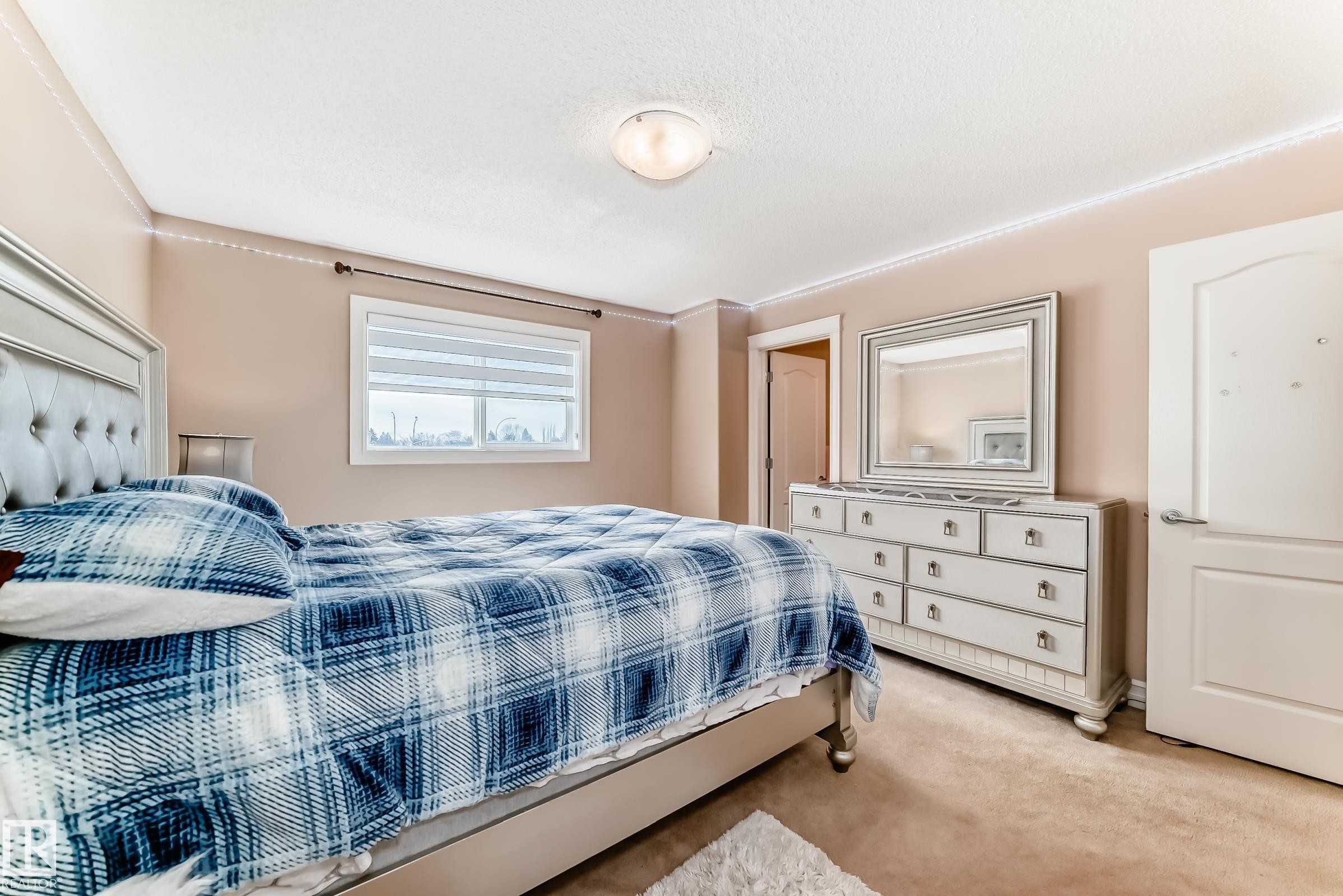 This room features carpeted flooring, a window with blinds, and a light-colored door with a decorative arch - 11415 167A Avenue Nw, Edmonton, AB - Indoor Photo Showing Bedroom