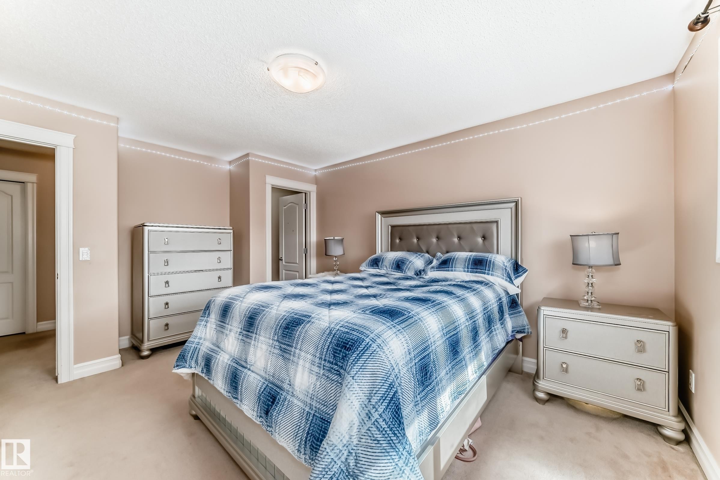 This inviting bedroom features neutral-toned walls, carpeted flooring, and crown molding - 11415 167A Avenue Nw, Edmonton, AB - Indoor Photo Showing Bedroom