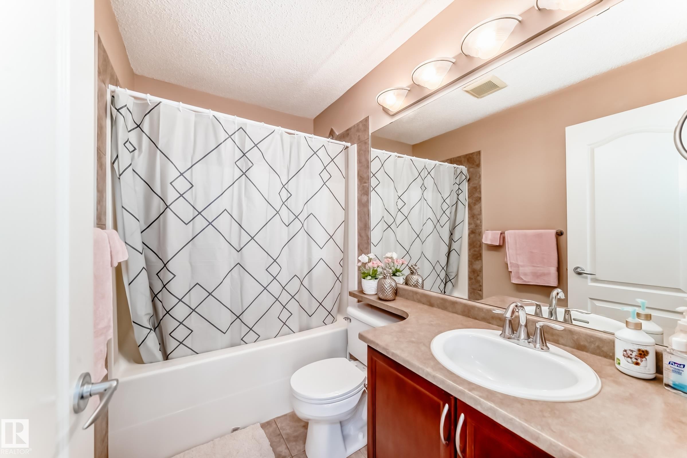 Bathroom featuring a vanity with an oval sink, a mirror with overhead lighting, and a bathtub with a shower curtain - 11415 167A Avenue Nw, Edmonton, AB - Indoor Photo Showing Bathroom