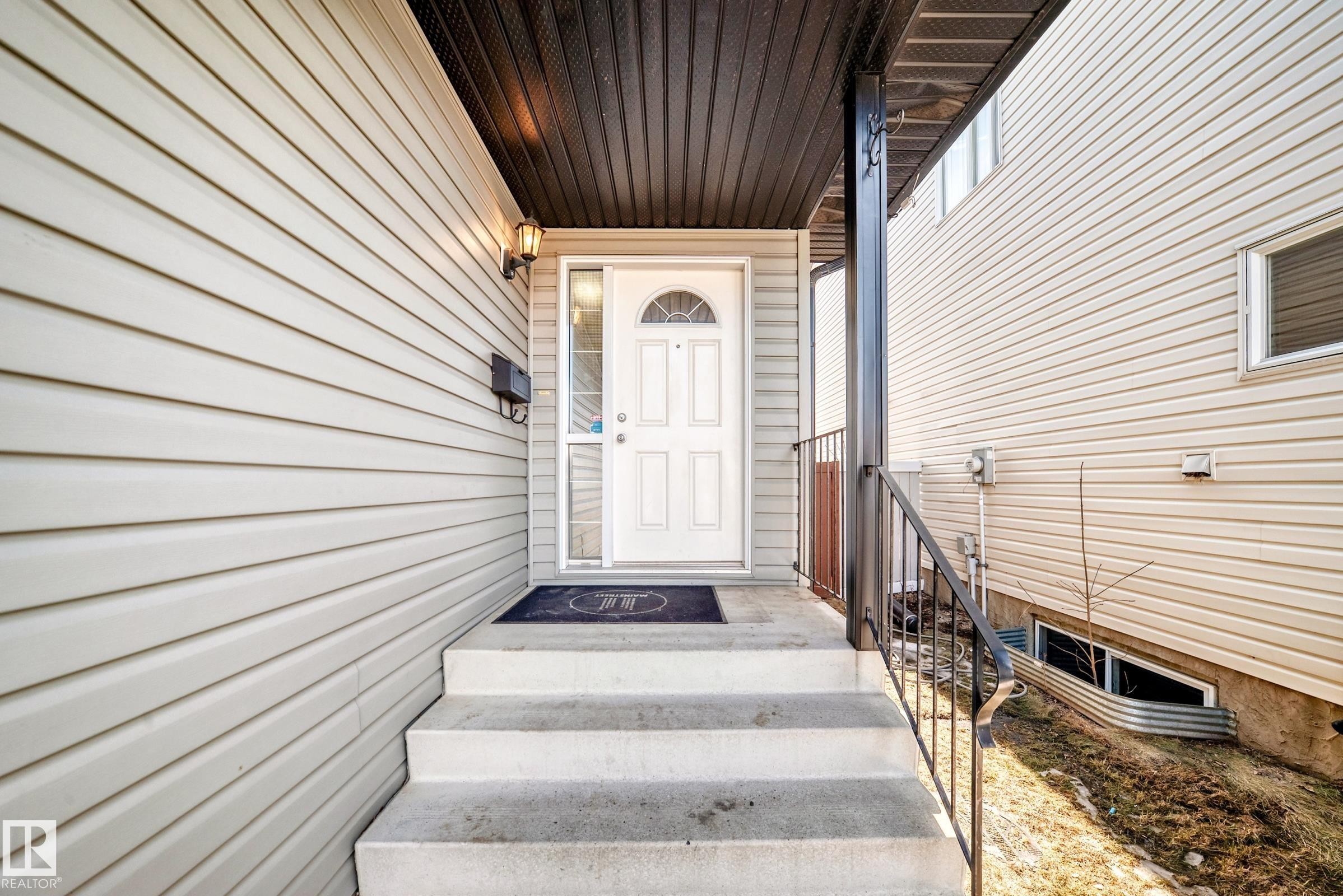 The property features a white paneled front door with an arched window, complemented by an exterior light fixture - 11415 167A Avenue Nw, Edmonton, AB - Outdoor With Exterior