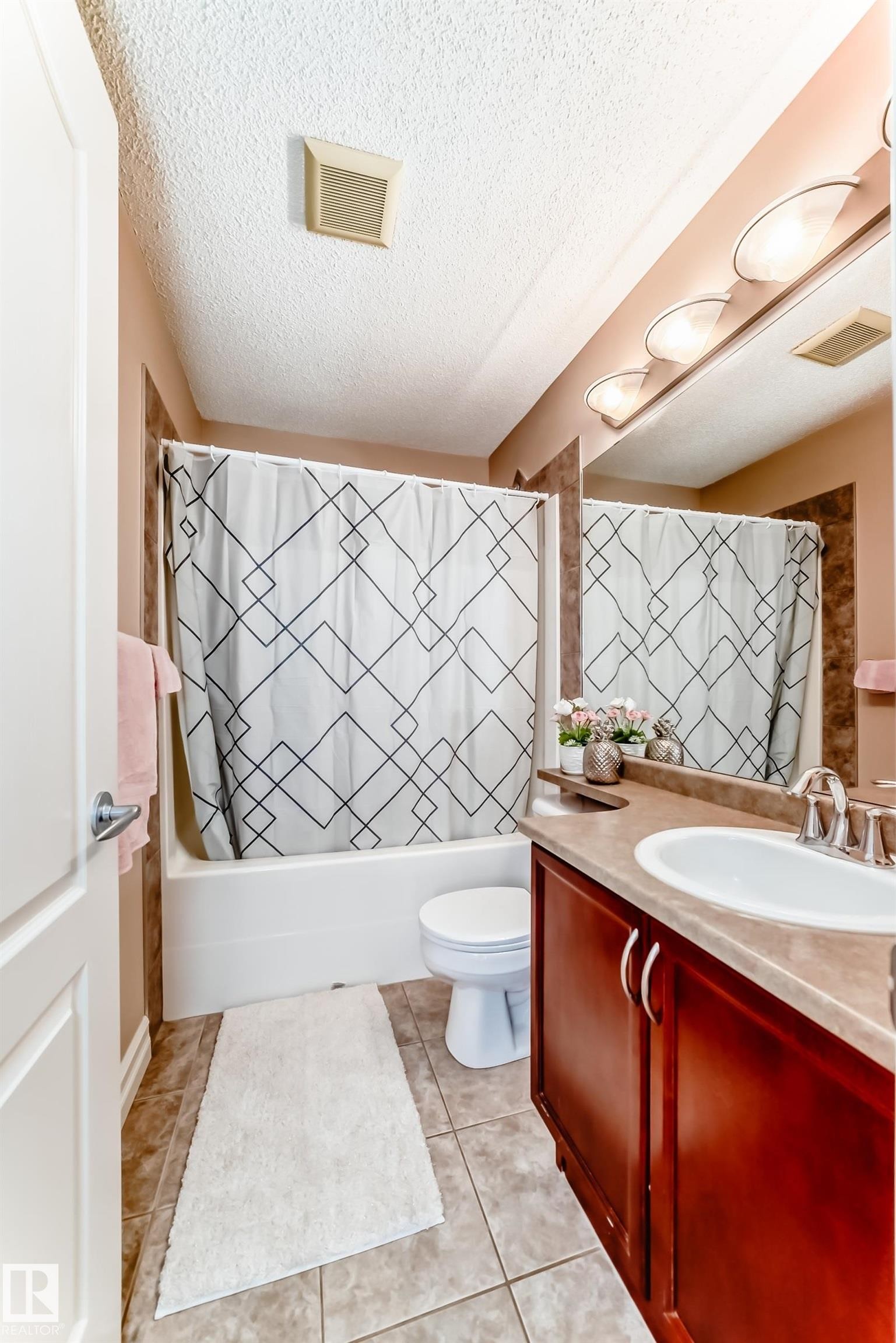 Bathroom featuring a vanity with a white sink, a mirror with overhead lighting, and a bathtub with a shower - 11415 167A Avenue Nw, Edmonton, AB - Indoor Photo Showing Bathroom