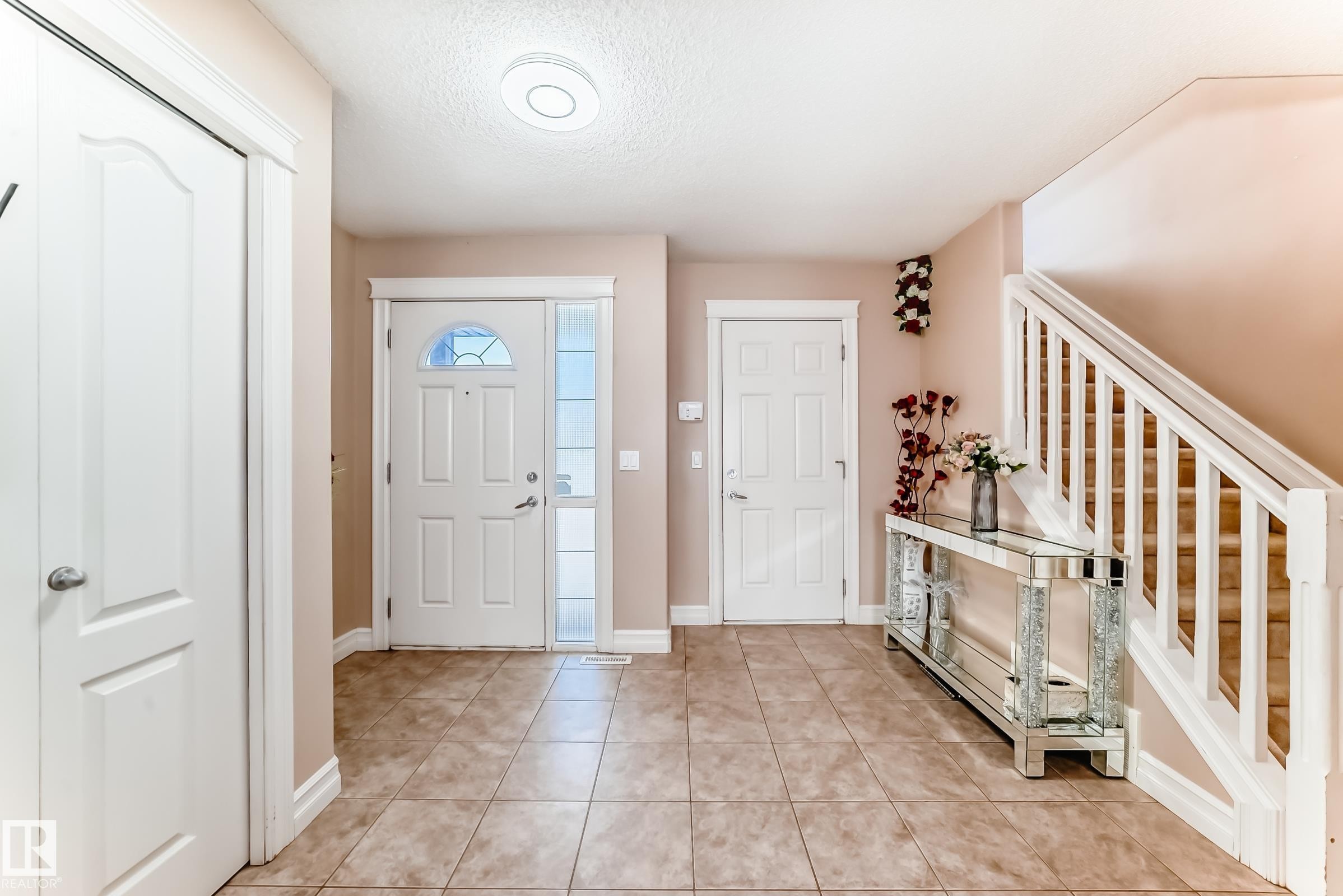 Welcoming entryway featuring a tiled floor, a white front door with a decorative glass insert, and a staircase with white railings - 11415 167A Avenue Nw, Edmonton, AB - Indoor Photo Showing Other Room
