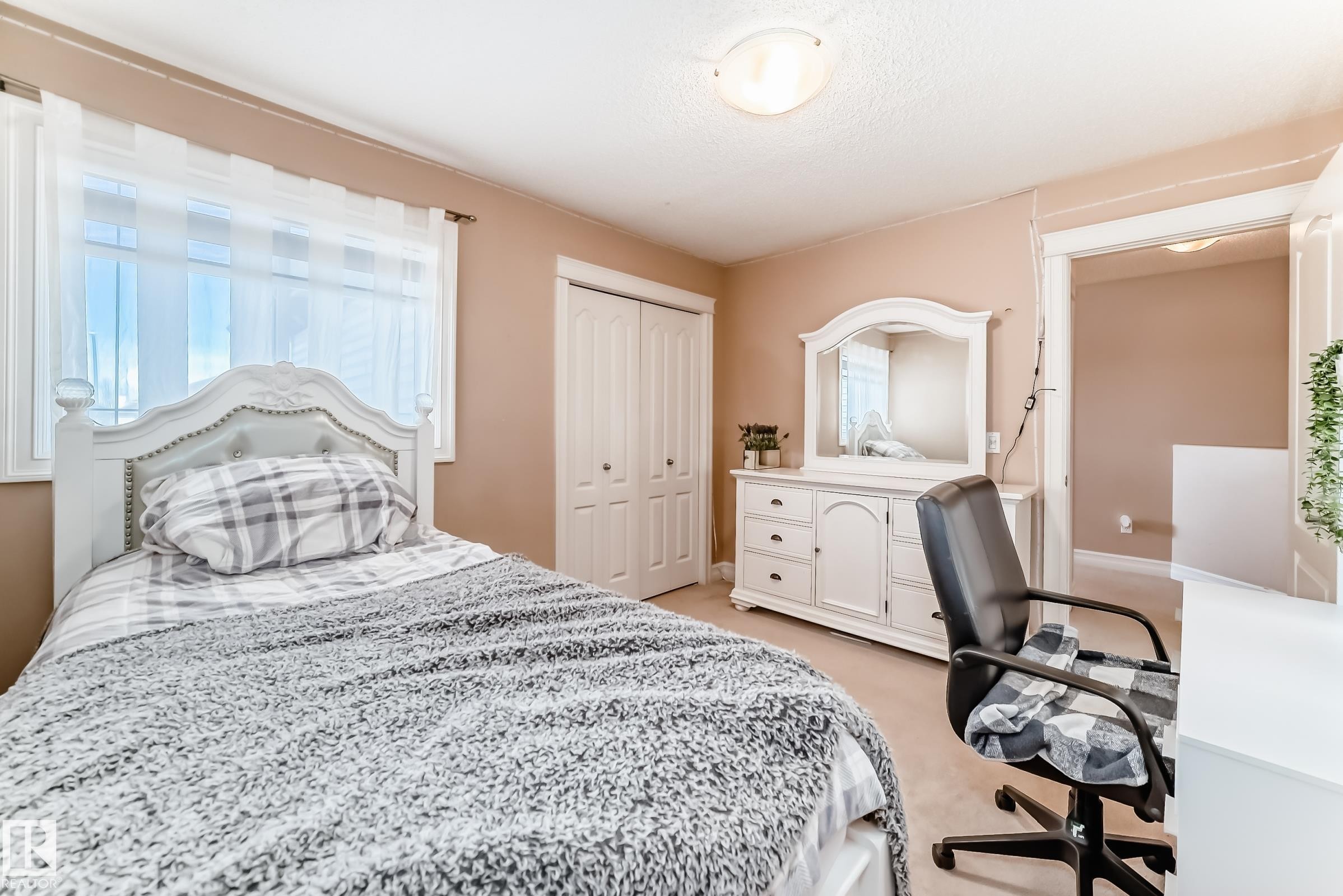 This room features a window with sheer white curtains, light tan walls, and carpeted flooring - 11415 167A Avenue Nw, Edmonton, AB - Indoor Photo Showing Bedroom