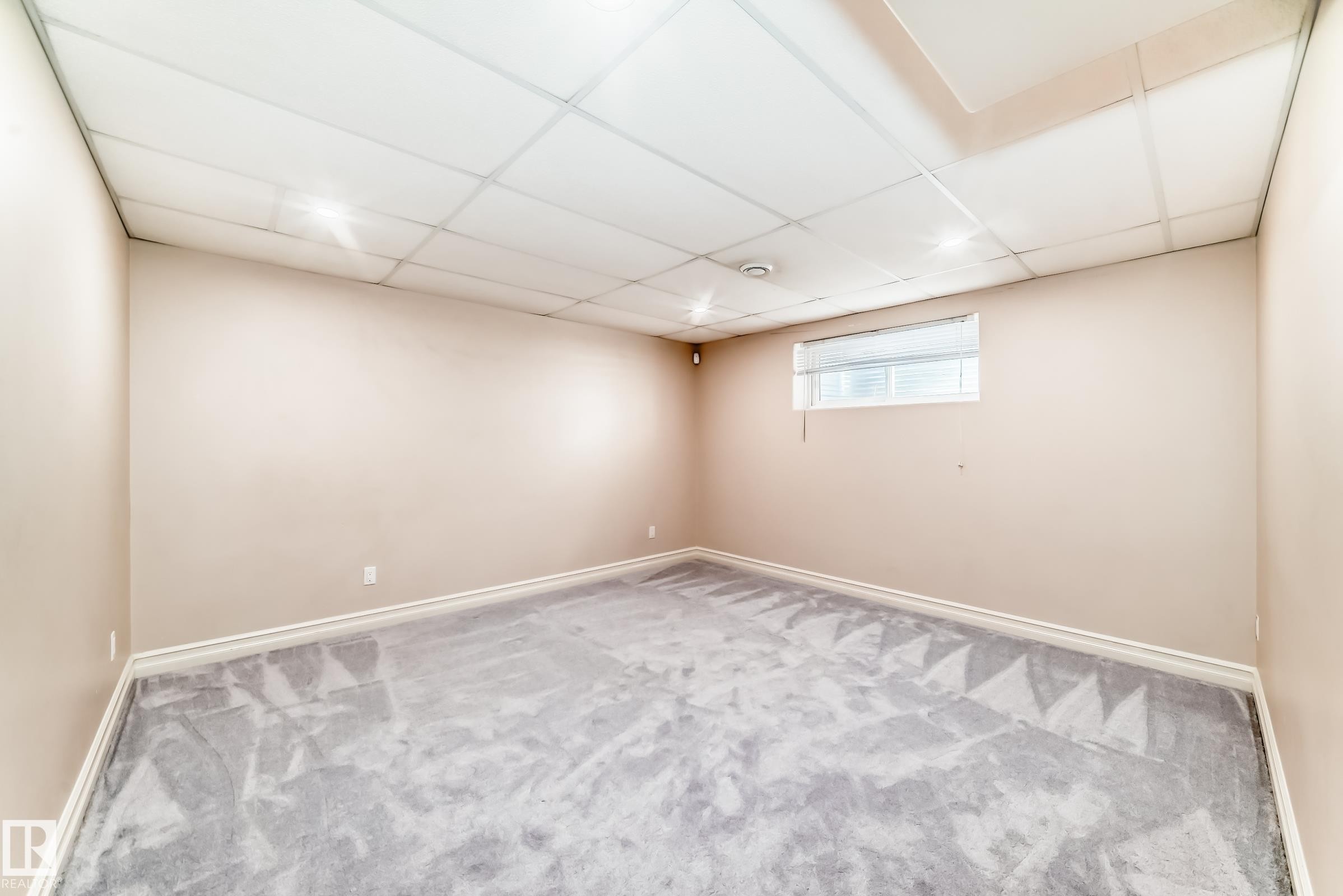 The property features a room with light grey carpet, a drop ceiling with recessed lighting, and a window with blinds - 11415 167A Avenue Nw, Edmonton, AB - Indoor