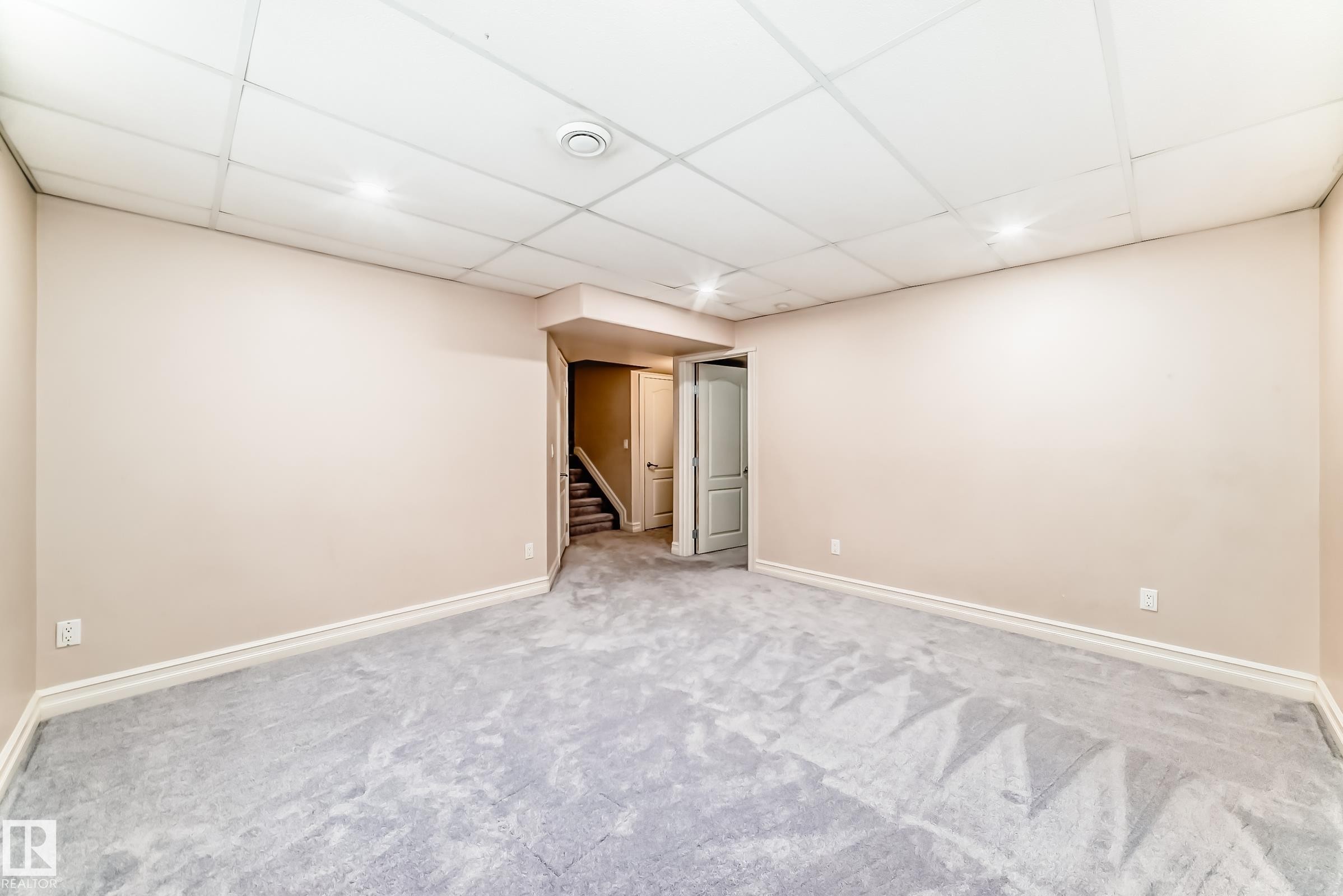 Spacious room with light-colored walls and plush grey carpeting, featuring recessed lighting and a drop ceiling - 11415 167A Avenue Nw, Edmonton, AB - Indoor