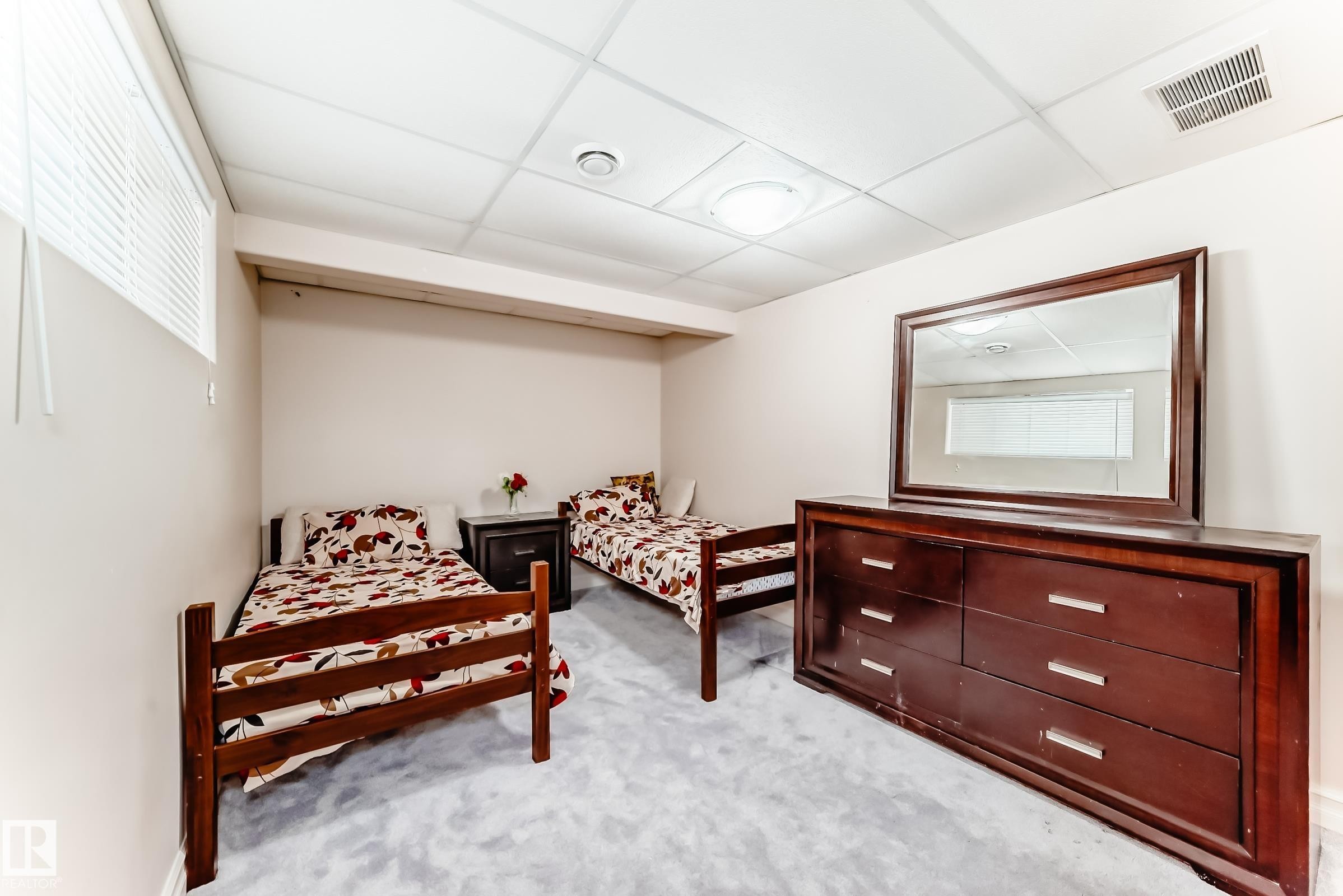 This inviting room features soft gray carpeting, light-colored walls, and a drop ceiling with recessed lighting - 11415 167A Avenue Nw, Edmonton, AB - Indoor