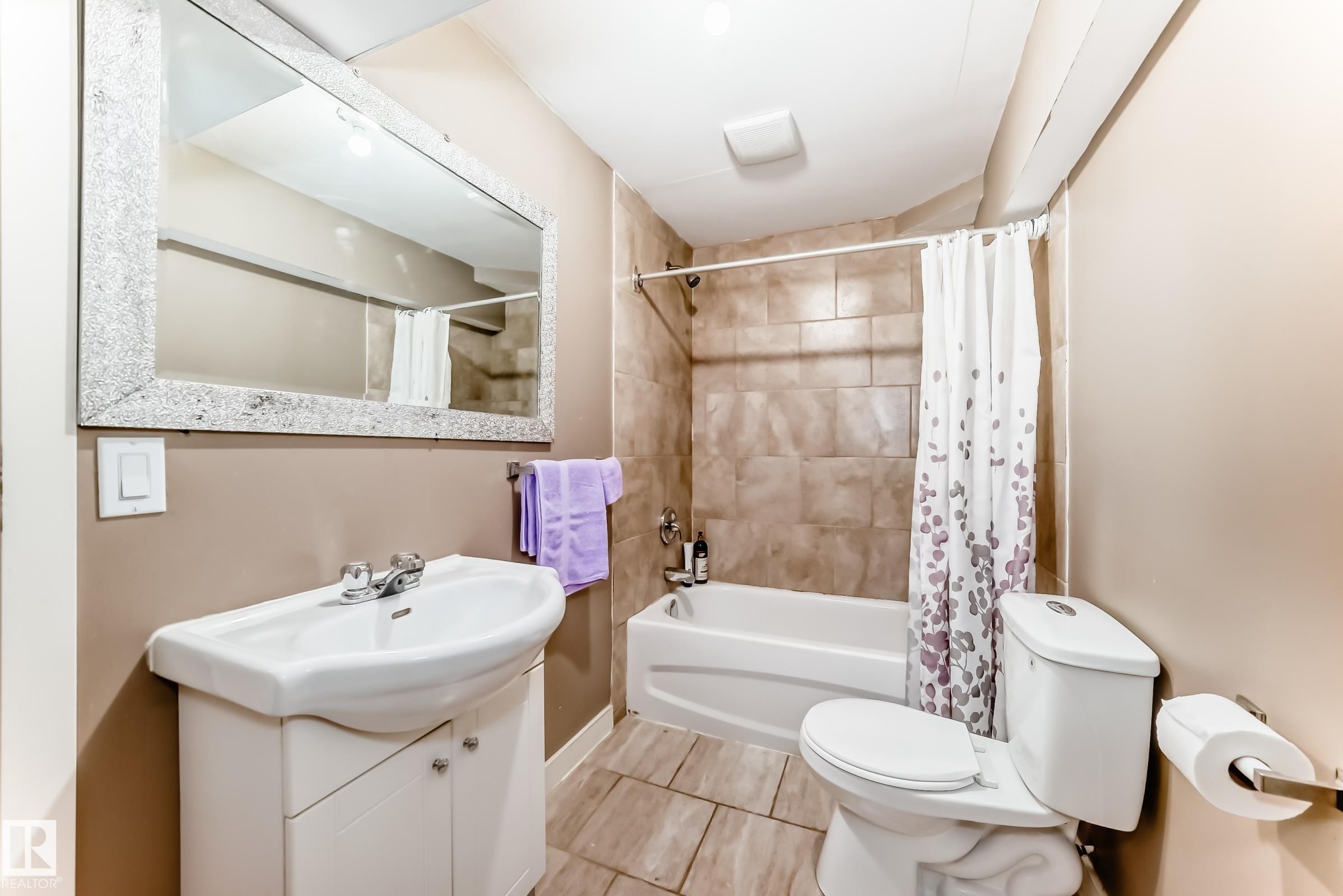 The bathroom features a white vanity with a ceramic sink, a mirror with a decorative frame, and a white toilet - 11415 167A Avenue Nw, Edmonton, AB - Indoor Photo Showing Bathroom