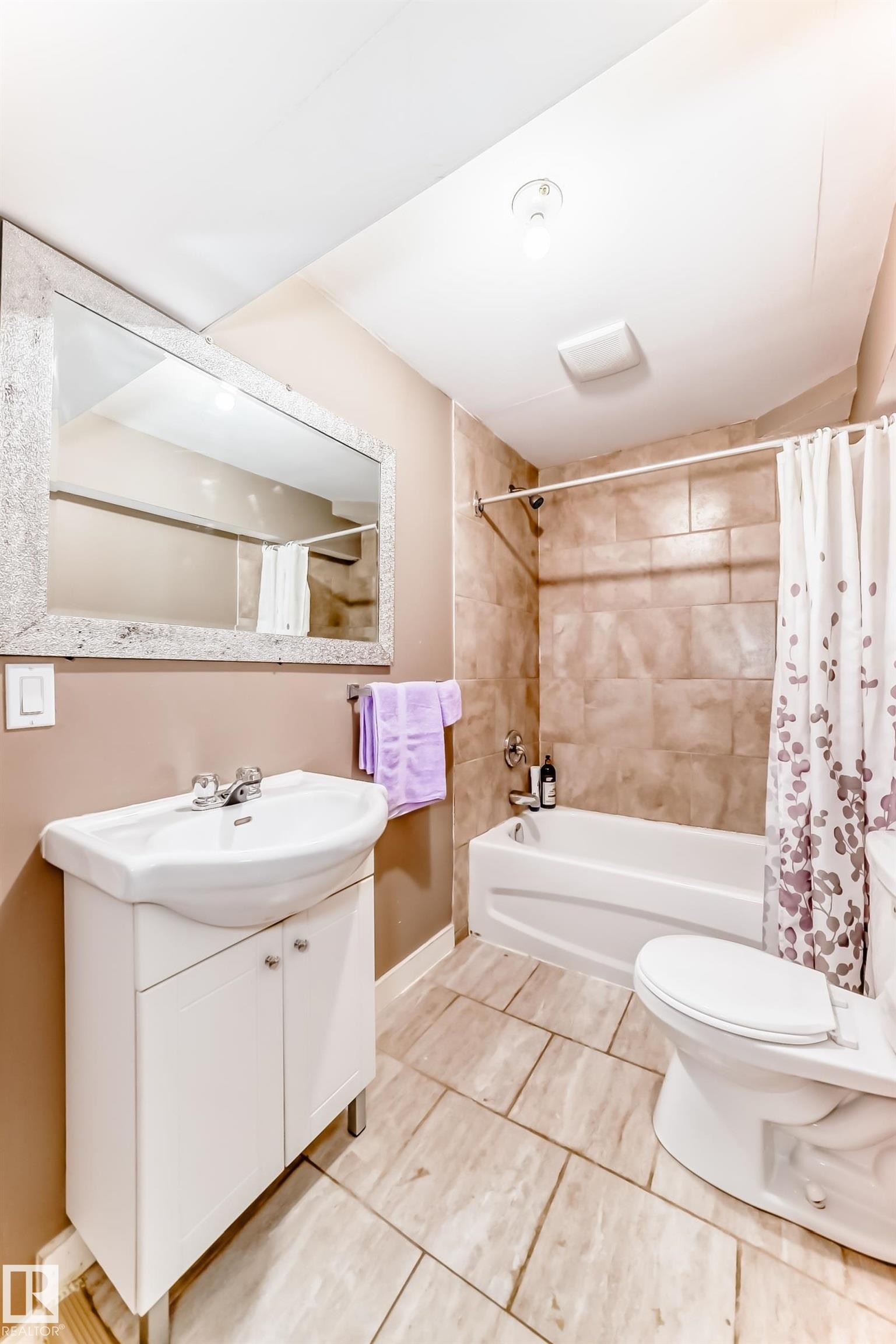 Bathroom featuring a vanity with an integrated sink, a bathtub with a shower, and tiled flooring - 11415 167A Avenue Nw, Edmonton, AB - Indoor Photo Showing Bathroom