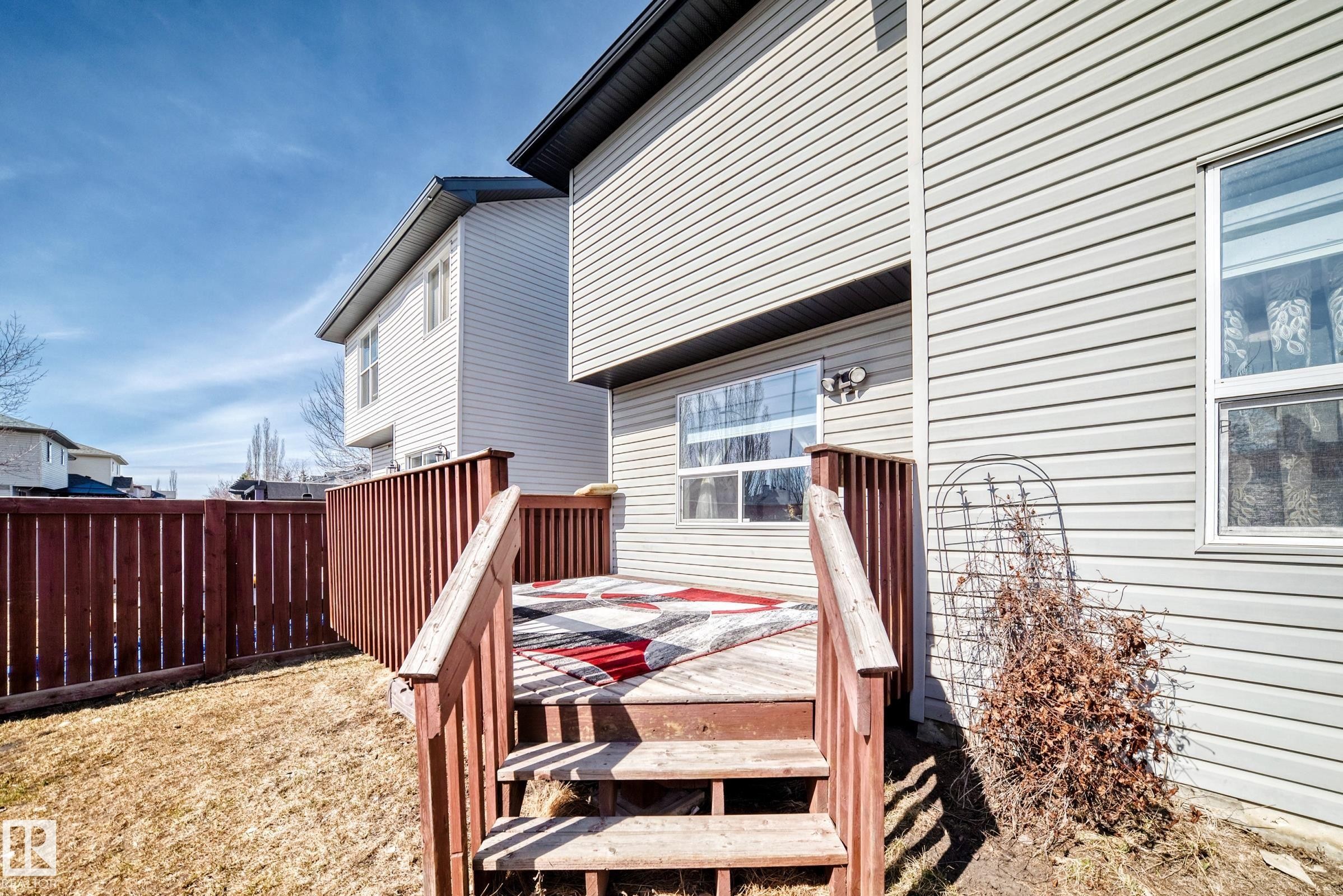 The property features a wooden deck with railing, accessible via stairs, leading to a yard area - 11415 167A Avenue Nw, Edmonton, AB - Outdoor With Exterior