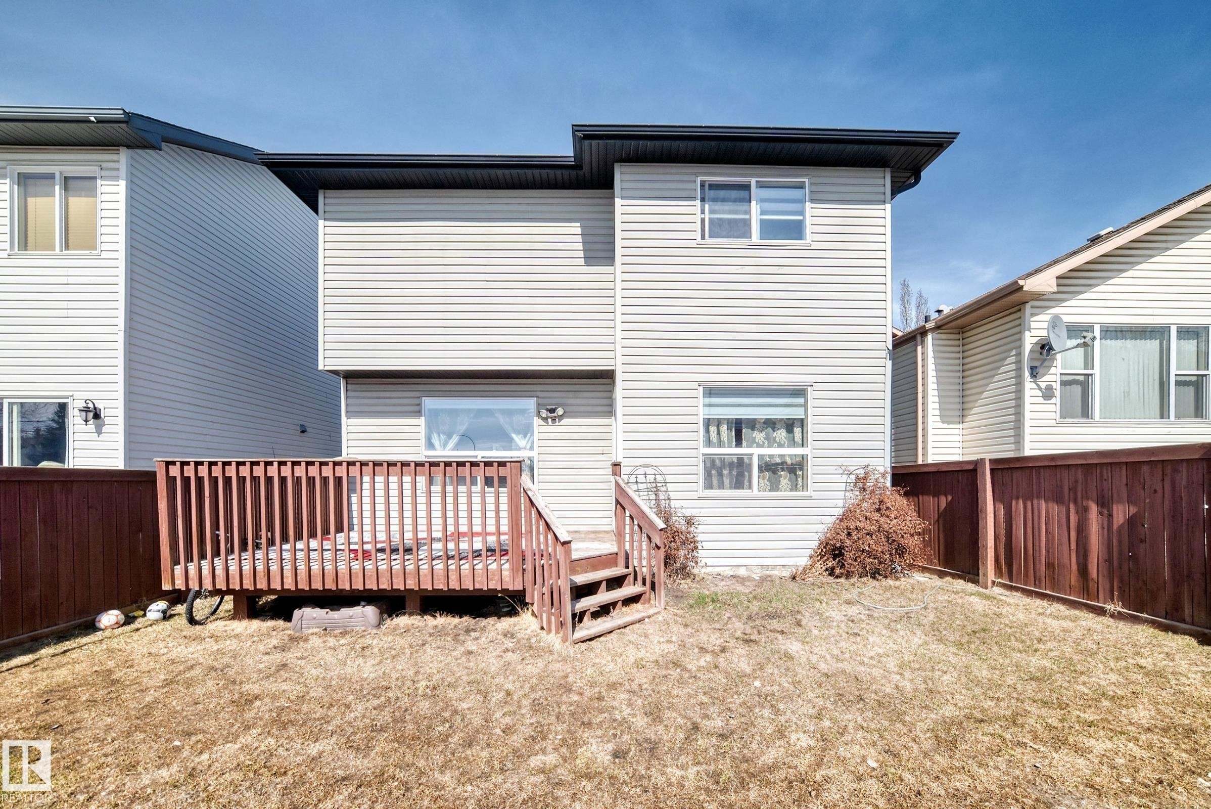 The property includes a wooden deck with railing, accessible via stairs - 11415 167A Avenue Nw, Edmonton, AB - Outdoor With Exterior