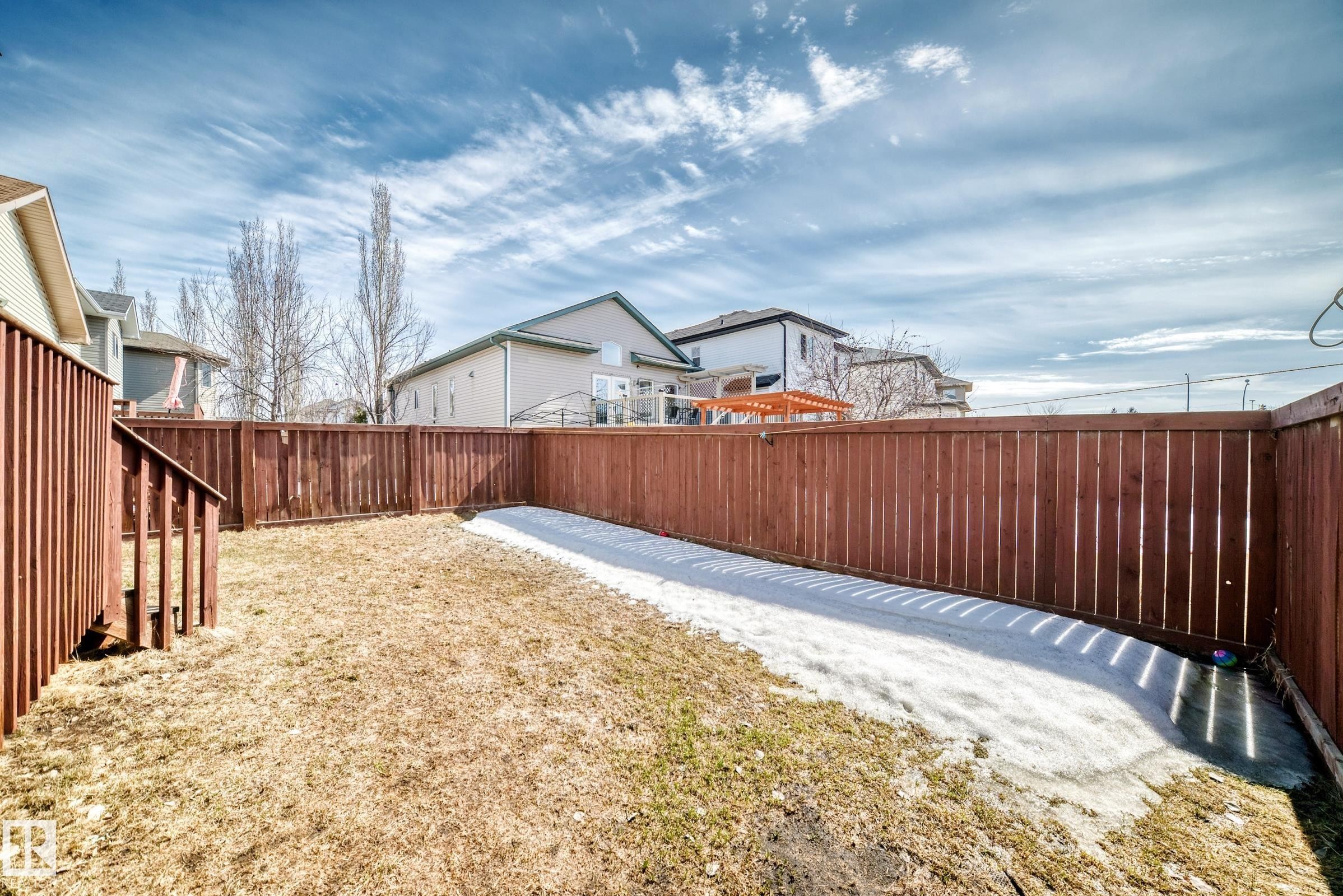 The property features a fenced yard with a combination of grass and a visible strip of snow - 11415 167A Avenue Nw, Edmonton, AB - Outdoor