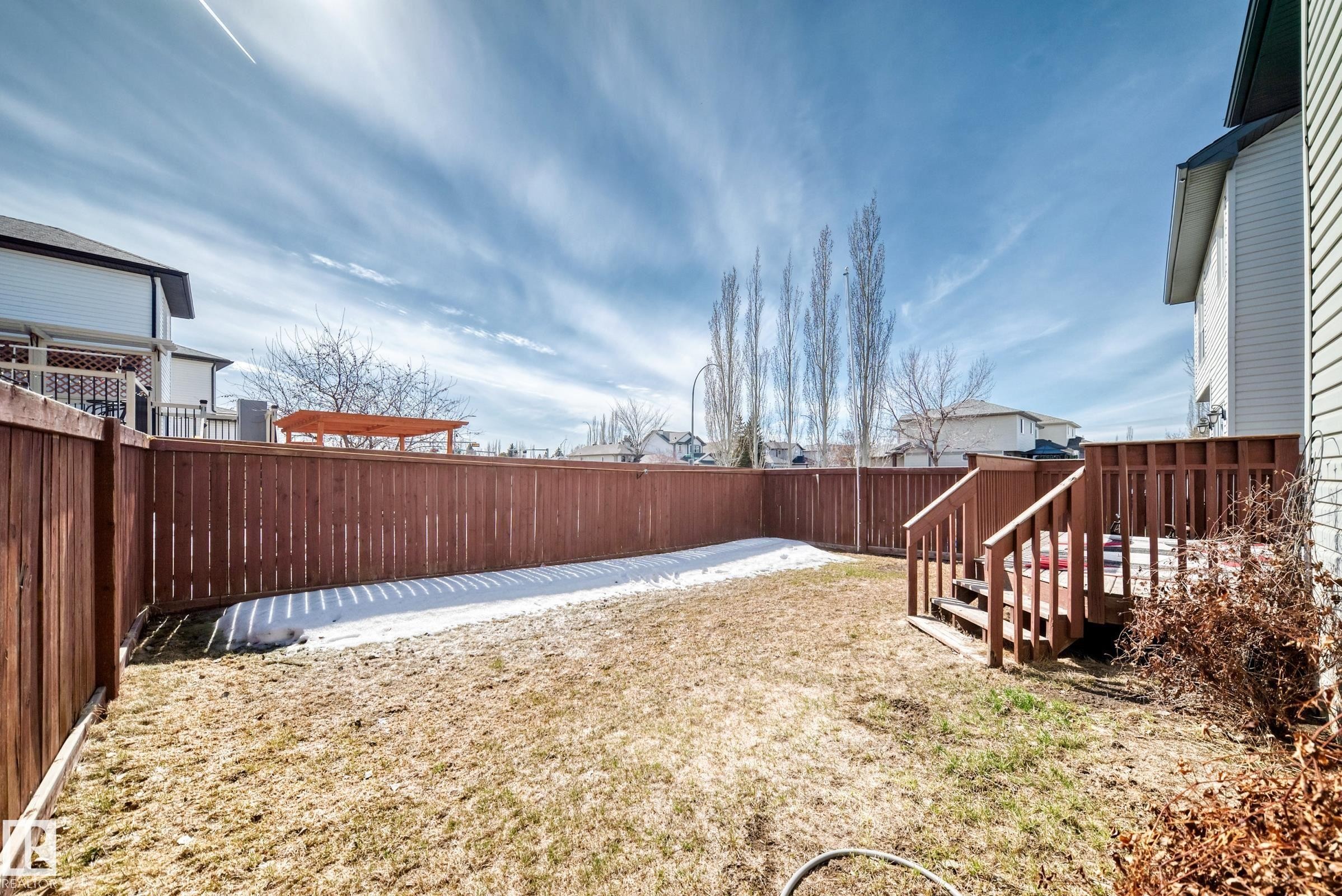 The property features a fenced yard with a deck and steps, and a partially grassed area - 11415 167A Avenue Nw, Edmonton, AB - Outdoor