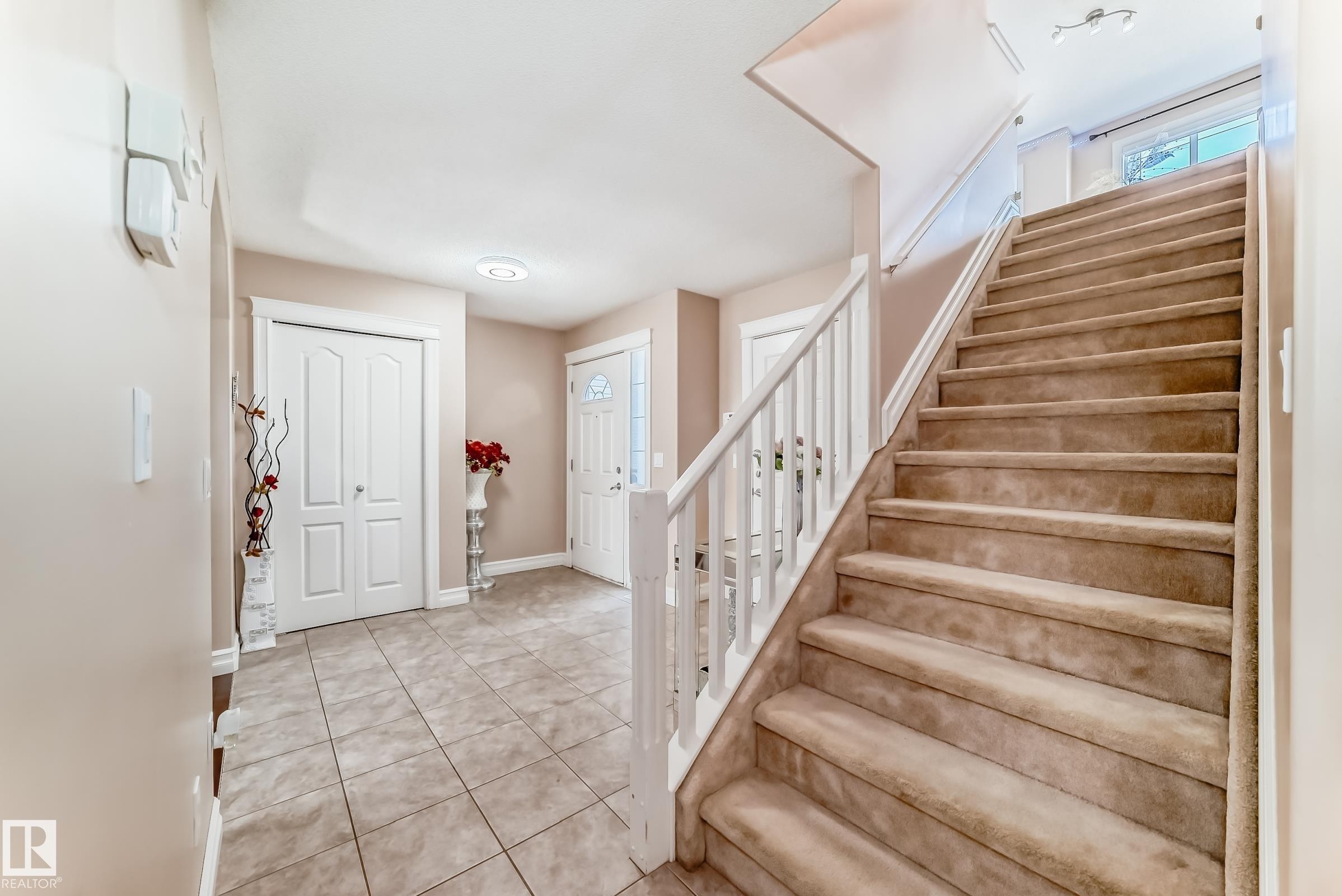 The property features an entryway with tiled flooring and a carpeted staircase with a white banister, leading to a window - 11415 167A Avenue Nw, Edmonton, AB - Indoor Photo Showing Other Room