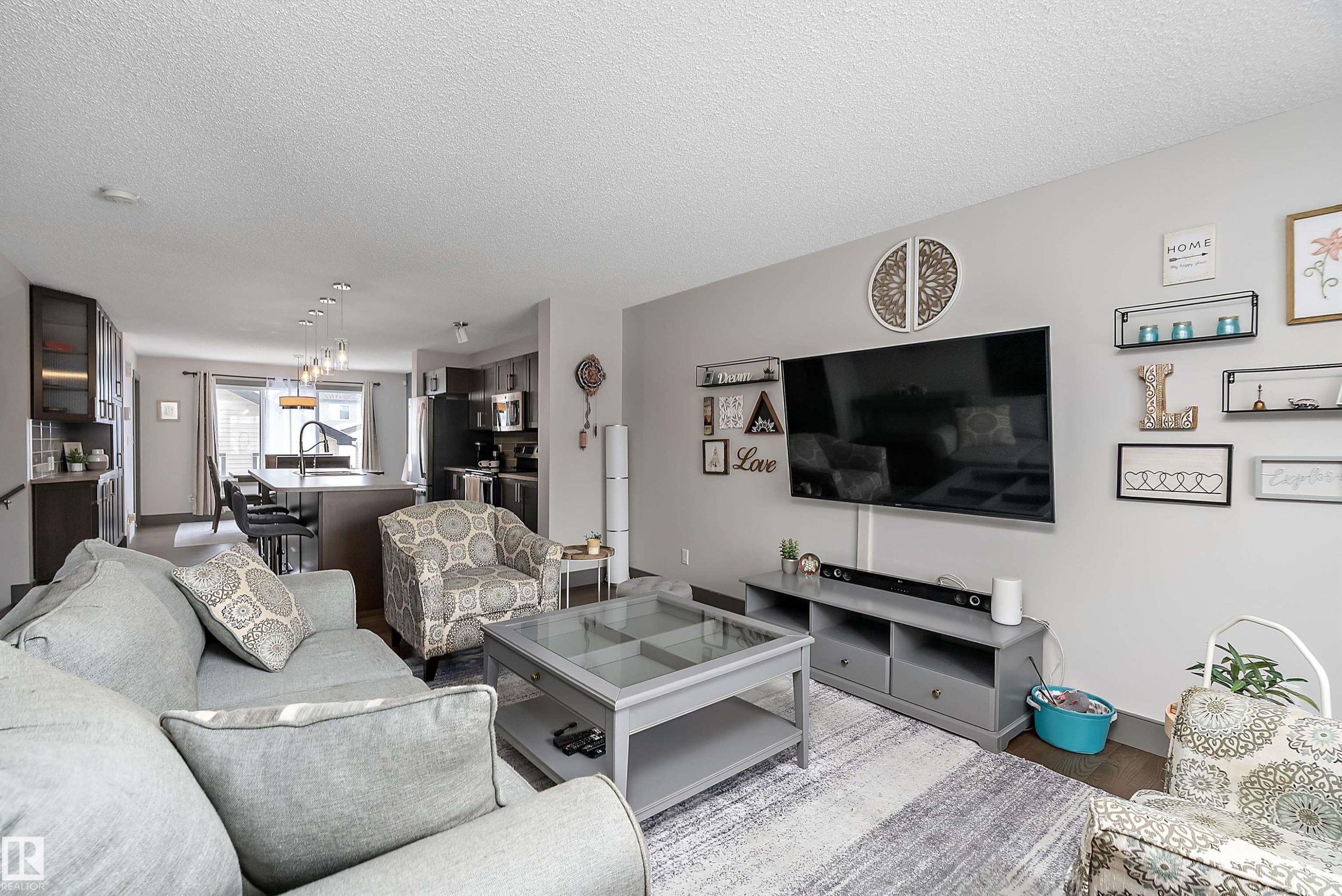 The open concept living area features light gray walls, dark wood flooring, and recessed lighting - 7776 Eifert Crescent Nw, Edmonton, AB - Indoor Photo Showing Living Room