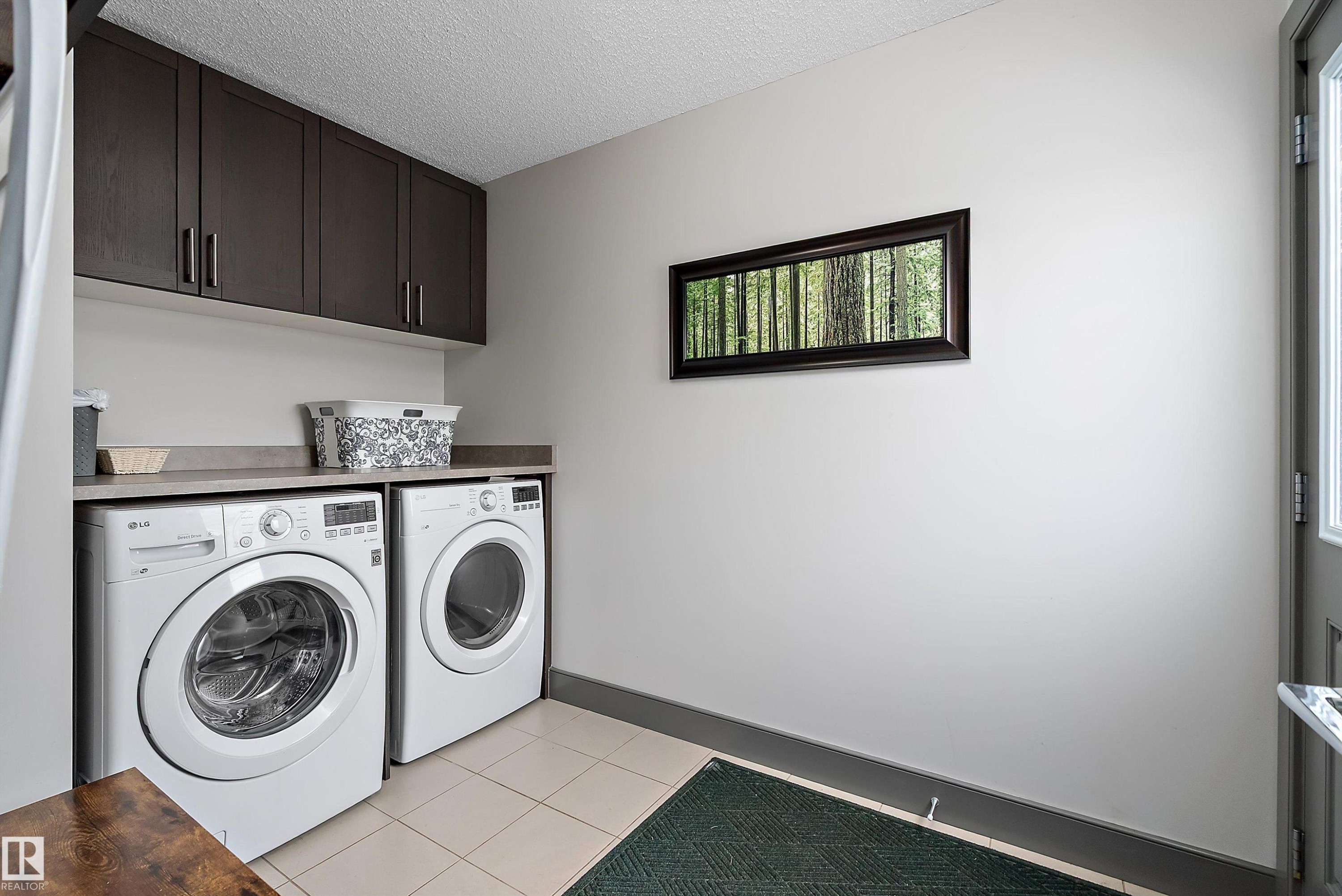 The laundry area features a washer and dryer, dark wood cabinetry, and a countertop space - 7776 Eifert Crescent Nw, Edmonton, AB - Indoor Photo Showing Laundry Room