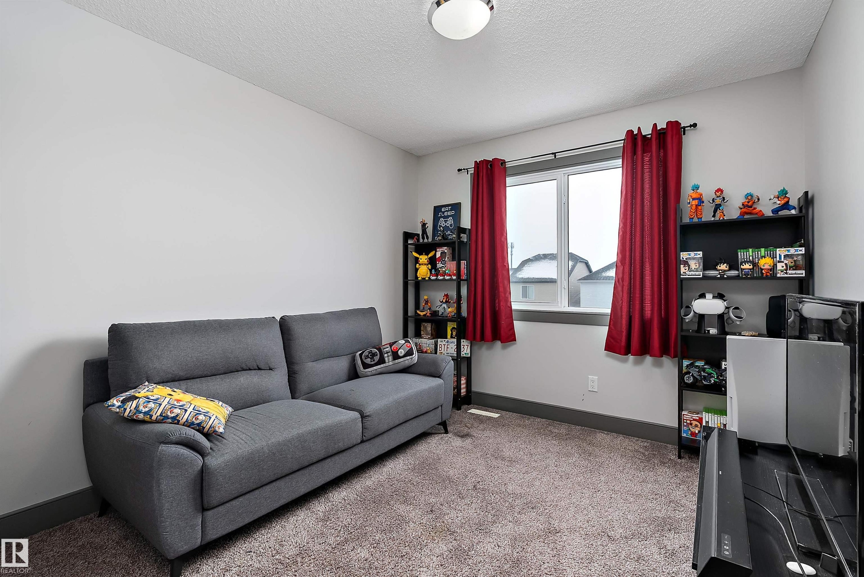 This room features light-colored walls and a window with red curtains - 7776 Eifert Crescent Nw, Edmonton, AB - Indoor