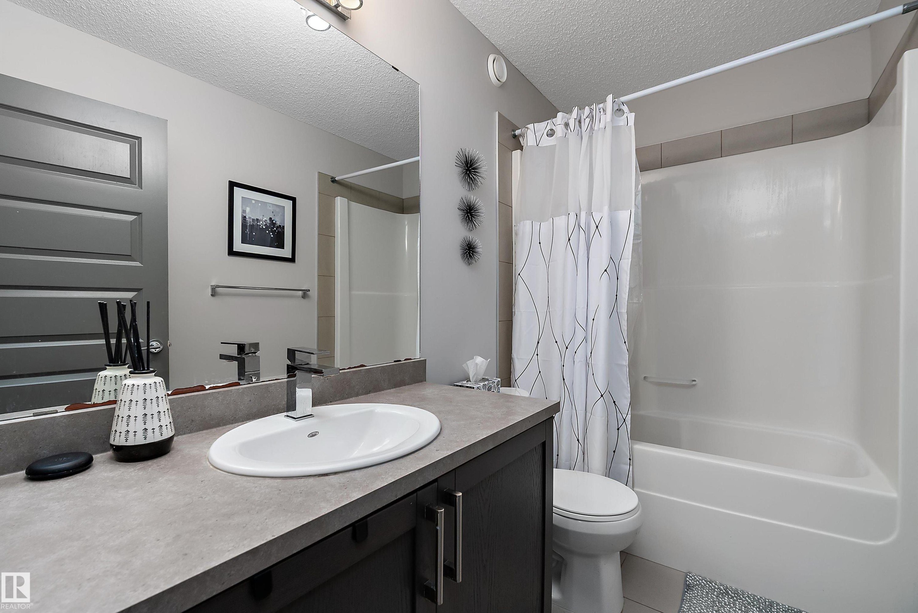 Bathroom featuring a dark wood vanity with a light-colored countertop and a white oval sink - 7776 Eifert Crescent Nw, Edmonton, AB - Indoor Photo Showing Bathroom