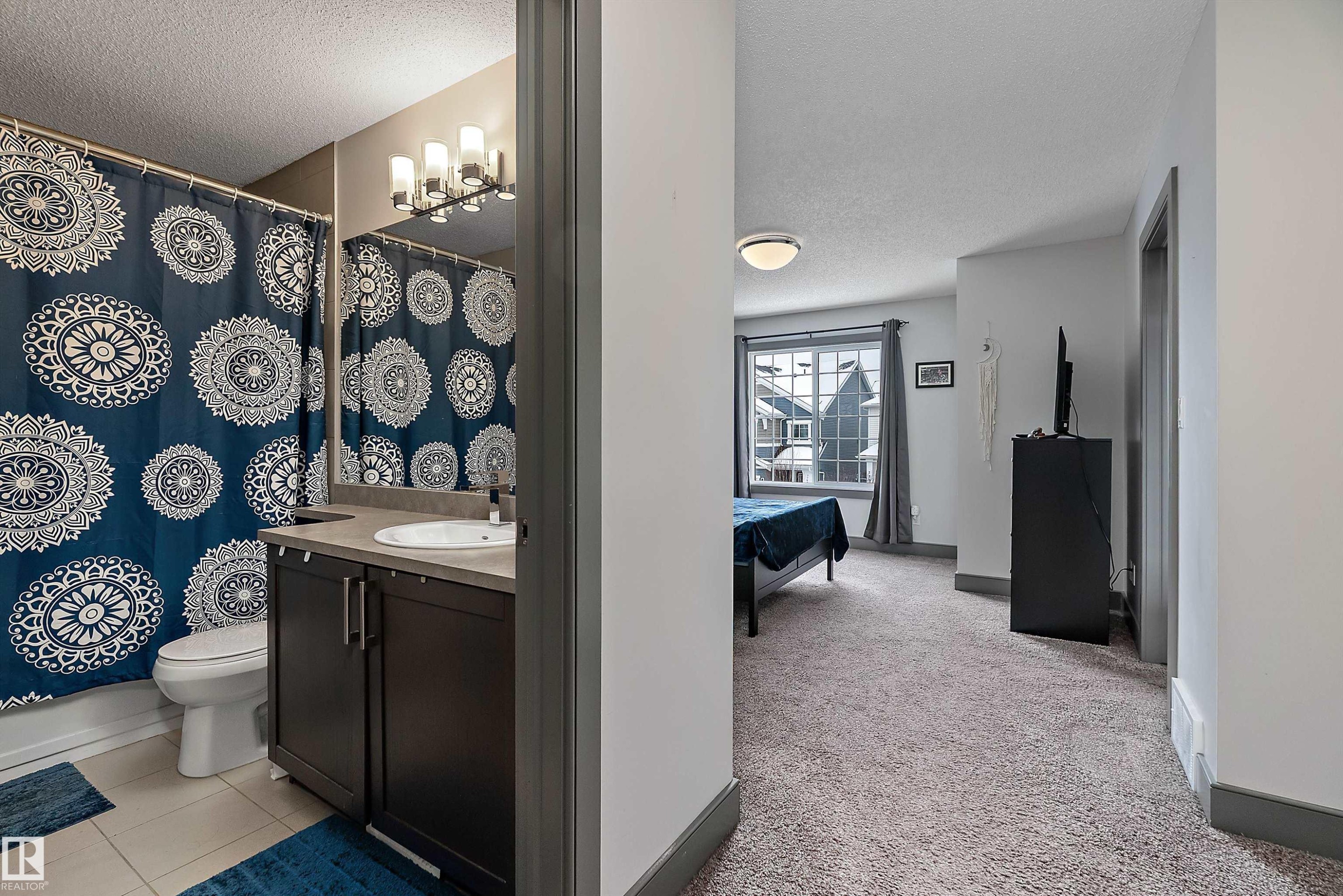 Bathroom featuring a dark wood vanity with a light countertop and a toilet, with a bedroom visible from the doorway - 7776 Eifert Crescent Nw, Edmonton, AB - Indoor Photo Showing Bathroom