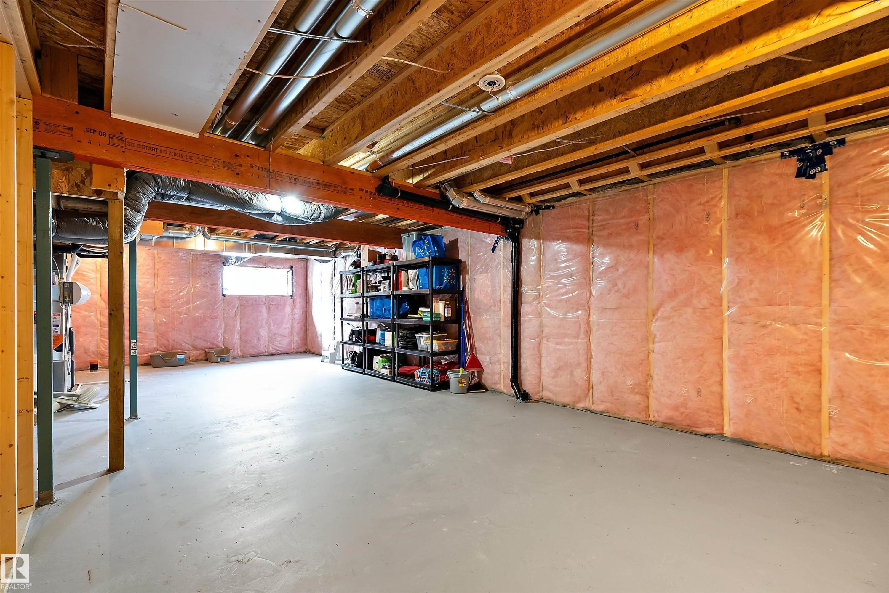 The property features an unfinished basement with exposed wooden beams, insulation along the walls, and a window providing natural light - 7776 Eifert Crescent Nw, Edmonton, AB - Indoor Photo Showing Basement