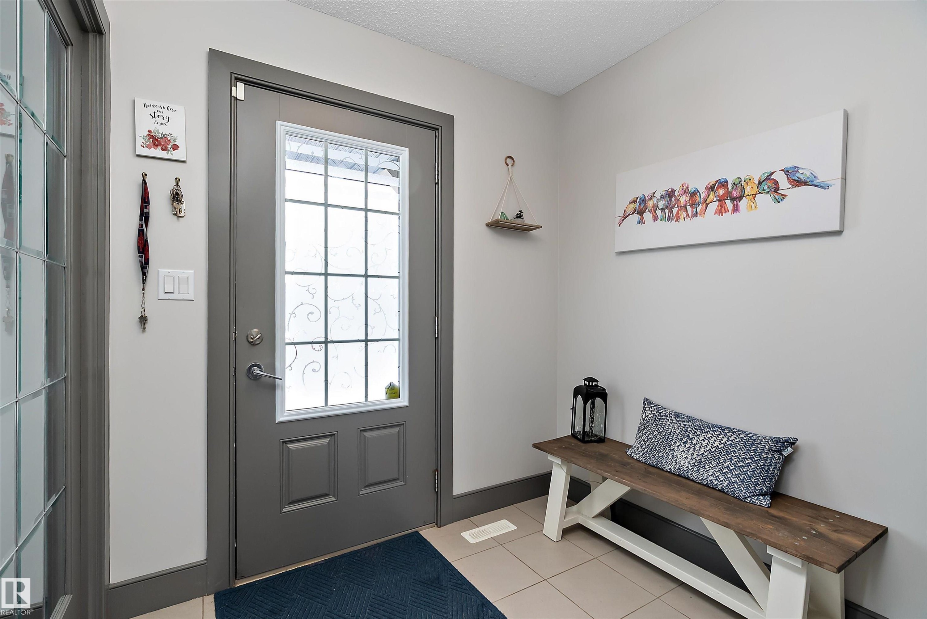Entryway featuring a grey front door with decorative glass inserts, light grey walls, and tiled flooring - 7776 Eifert Crescent Nw, Edmonton, AB - Indoor Photo Showing Other Room