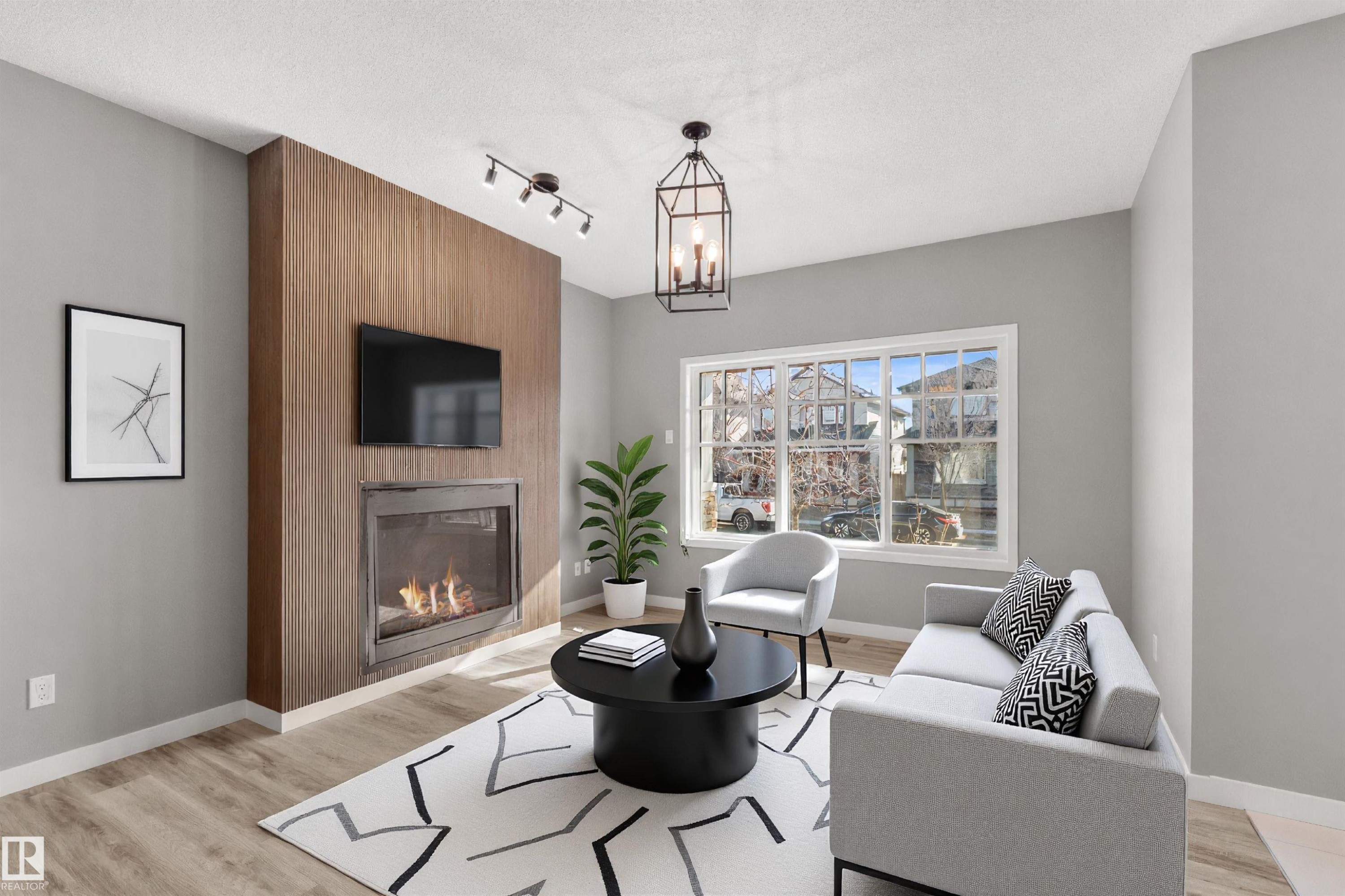 The living area features a fireplace with a wood-paneled surround, light-colored flooring, and a large window providing views of the neighborhood - 4016 Allan Crescent, Edmonton, AB - Indoor Photo Showing Living Room With Fireplace