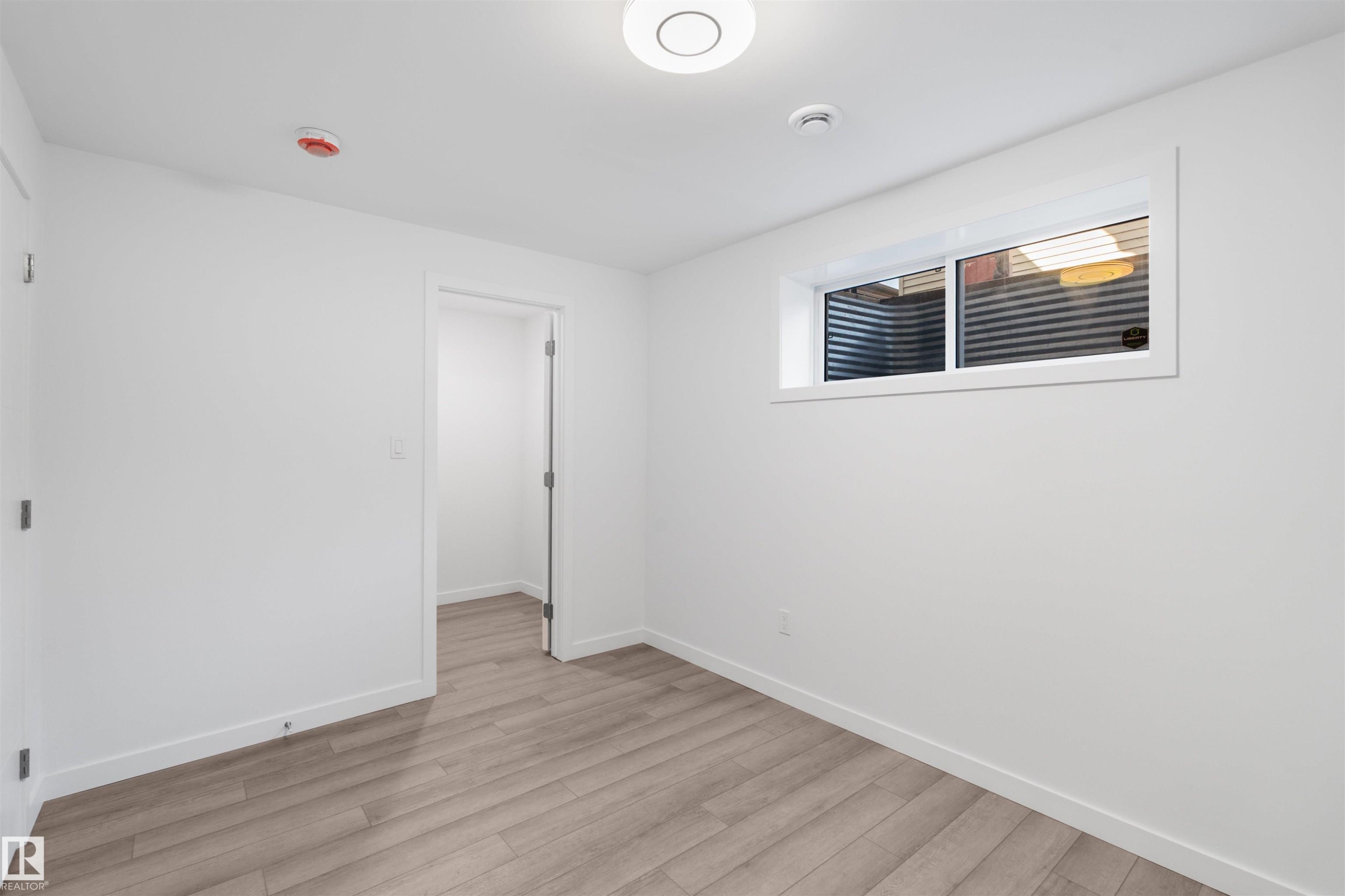 This room features light-toned wood-style flooring, a window, and white walls - 4016 Allan Crescent, Edmonton, AB - Indoor Photo Showing Other Room
