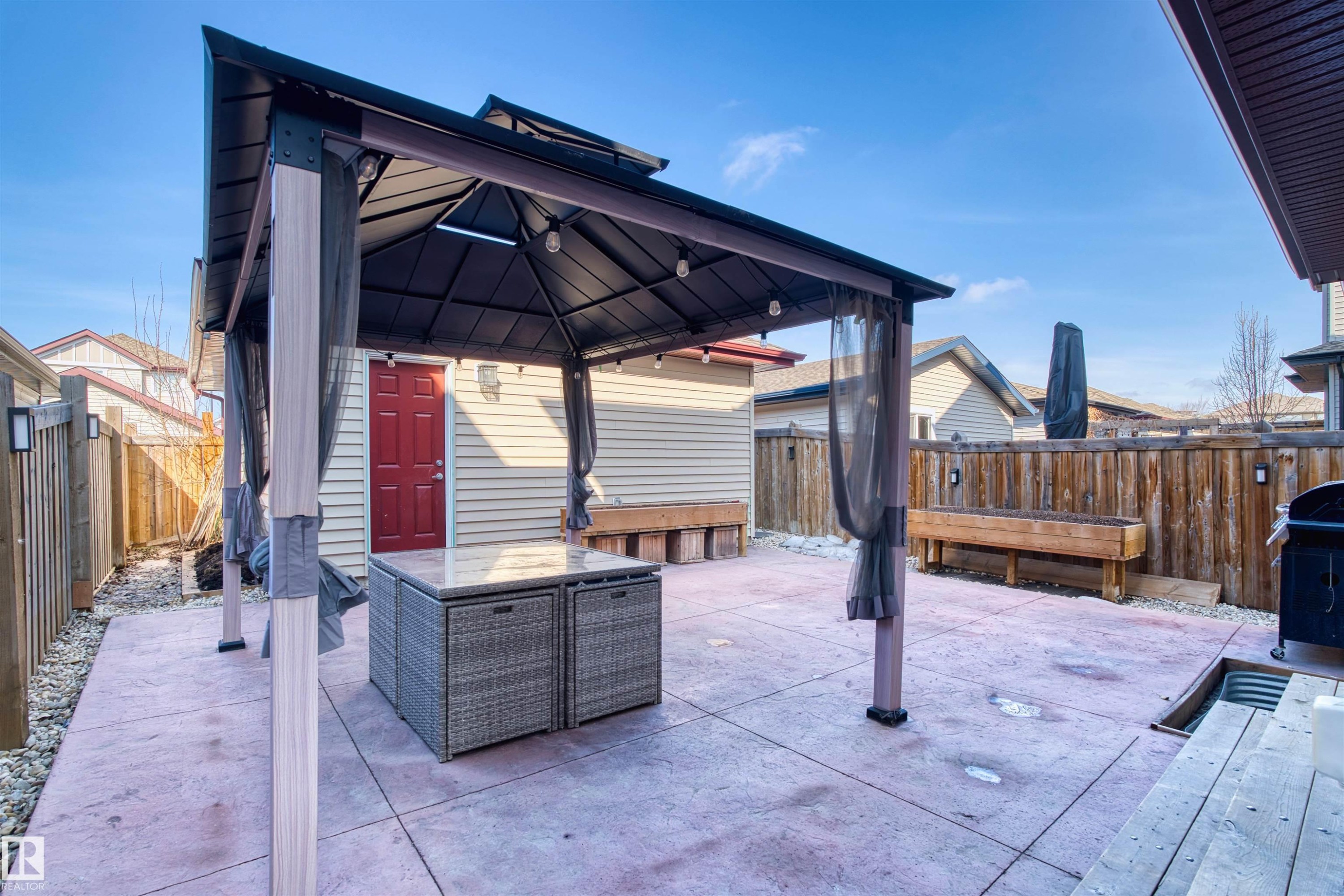 The property features a spacious patio area with a gazebo, a privacy fence, and an exterior red door - 4016 Allan Crescent, Edmonton, AB - Outdoor With Deck Patio Veranda With Exterior
