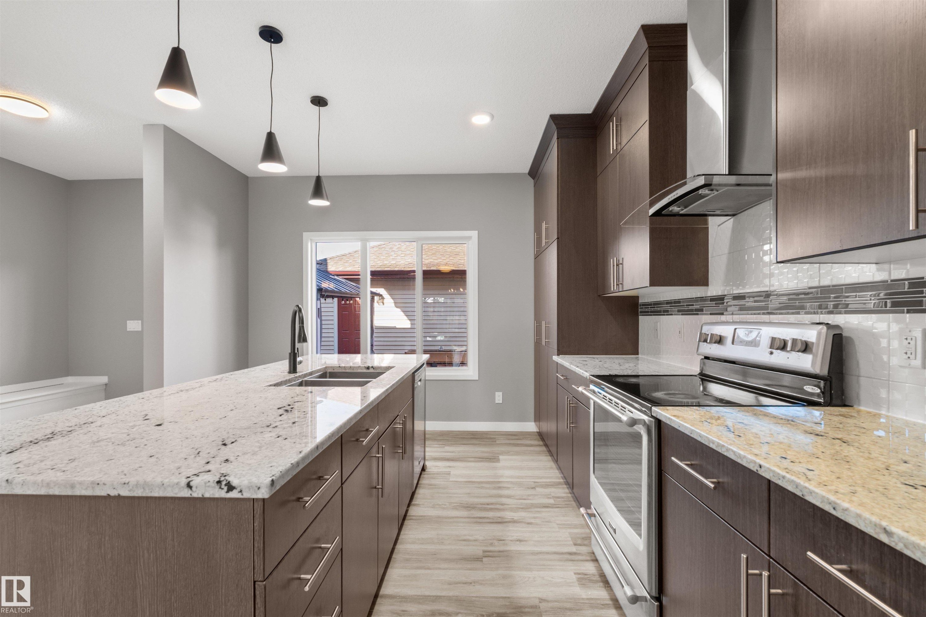 The kitchen features an expansive island with a double basin sink and a light-toned granite countertop - 4016 Allan Crescent, Edmonton, AB - Indoor Photo Showing Kitchen With Double Sink With Upgraded Kitchen
