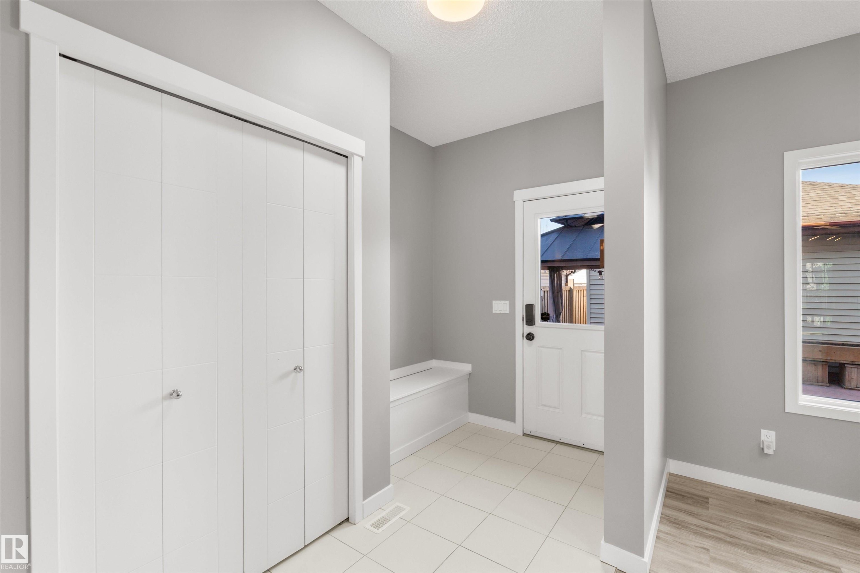 Entryway featuring light grey walls, white bi-fold doors, and a window providing natural light - 4016 Allan Crescent, Edmonton, AB - Indoor Photo Showing Other Room