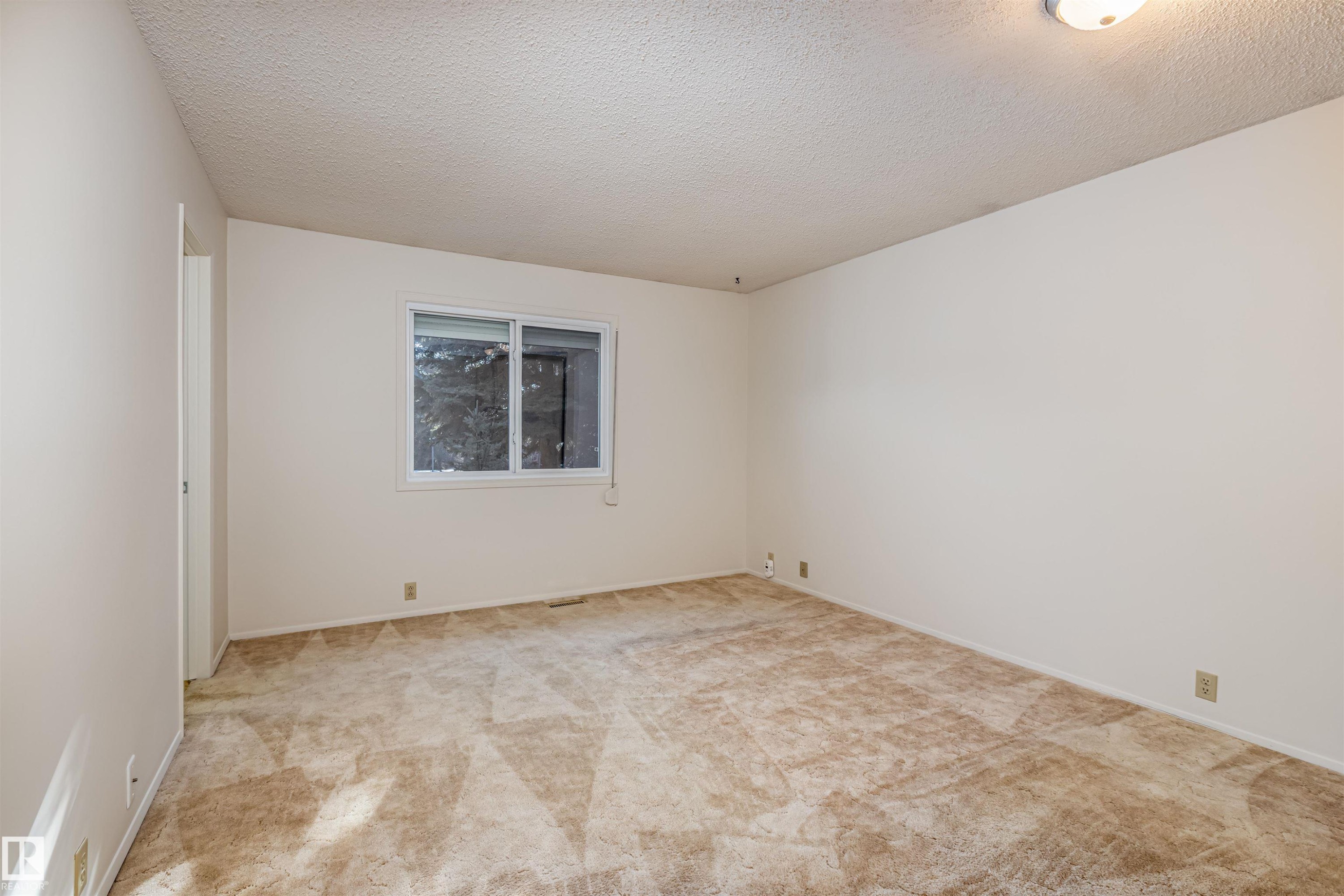 This room features neutral-toned carpeting, a window providing natural light, and a white ceiling with an overhead light fixture - 108 Forest Grove, St. Albert, AB - Indoor Photo Showing Other Room