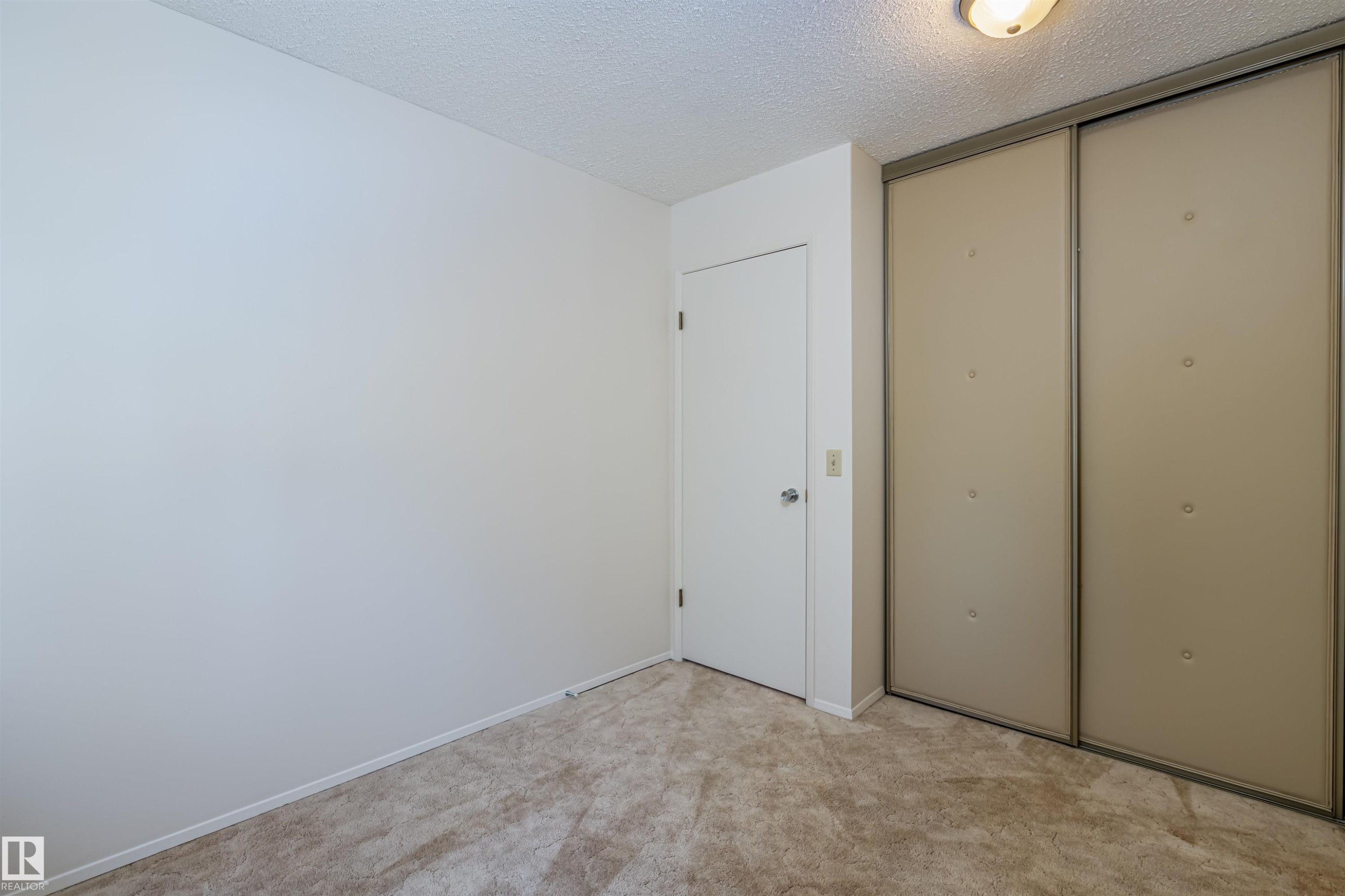 This room features carpeted flooring, a white interior door with a silver handle, and a large closet with sliding doors - 108 Forest Grove, St. Albert, AB - Indoor Photo Showing Other Room