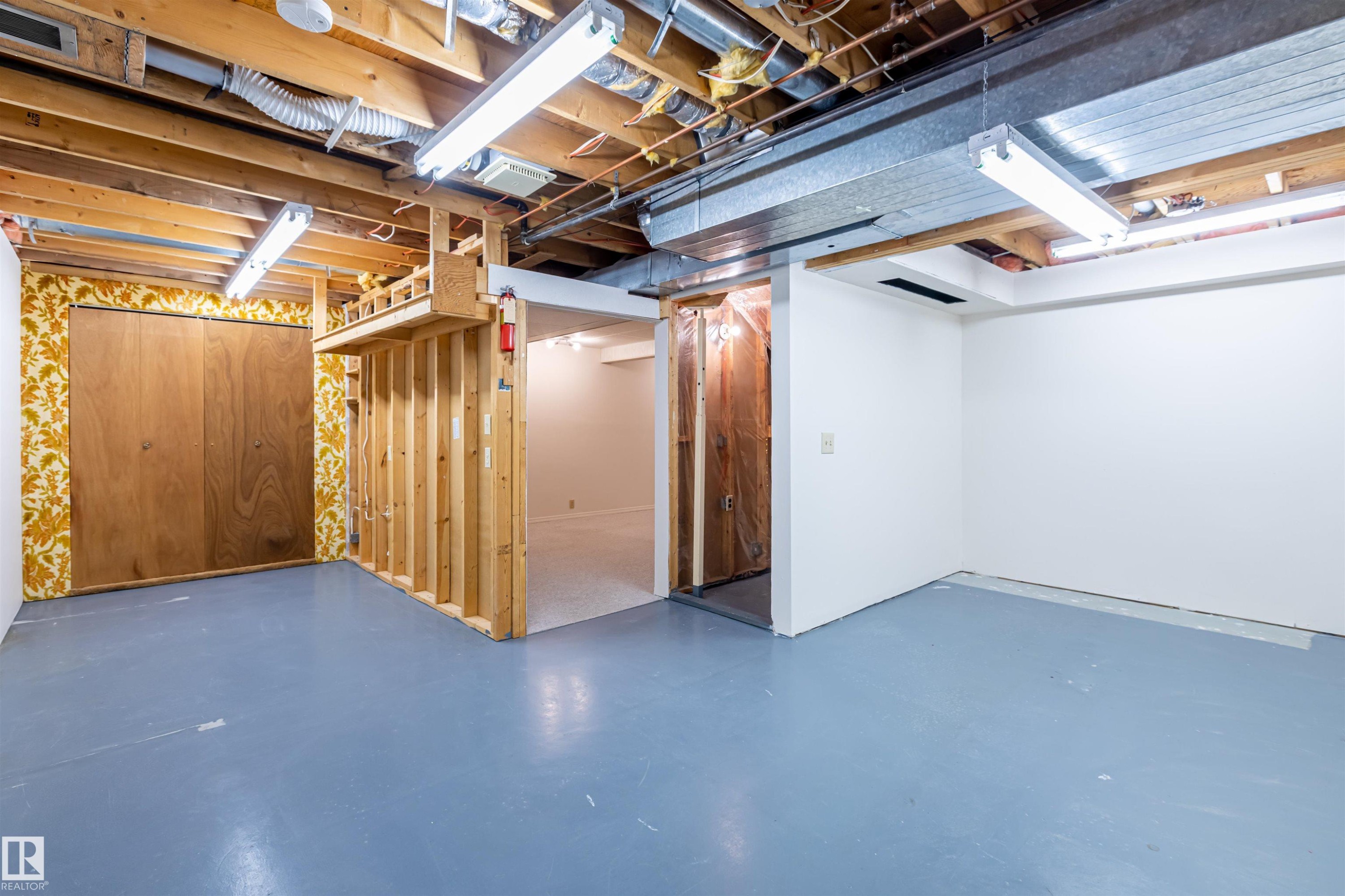 The property features an unfinished basement with painted concrete floors and exposed ceiling joists - 108 Forest Grove, St. Albert, AB - Indoor Photo Showing Basement