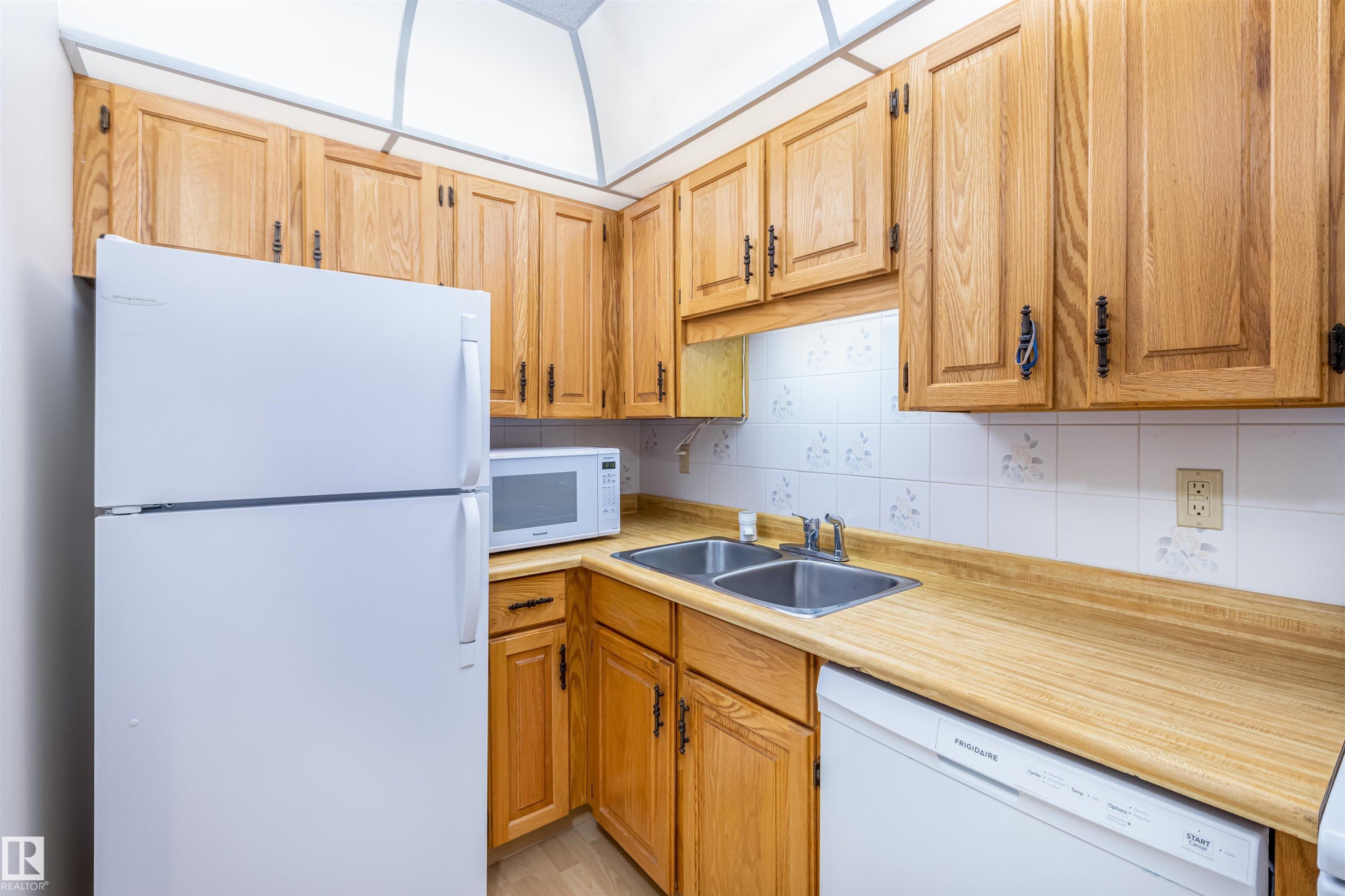 The kitchen features wooden cabinetry, white appliances, and a double basin sink - 108 Forest Grove, St. Albert, AB - Indoor Photo Showing Kitchen With Double Sink